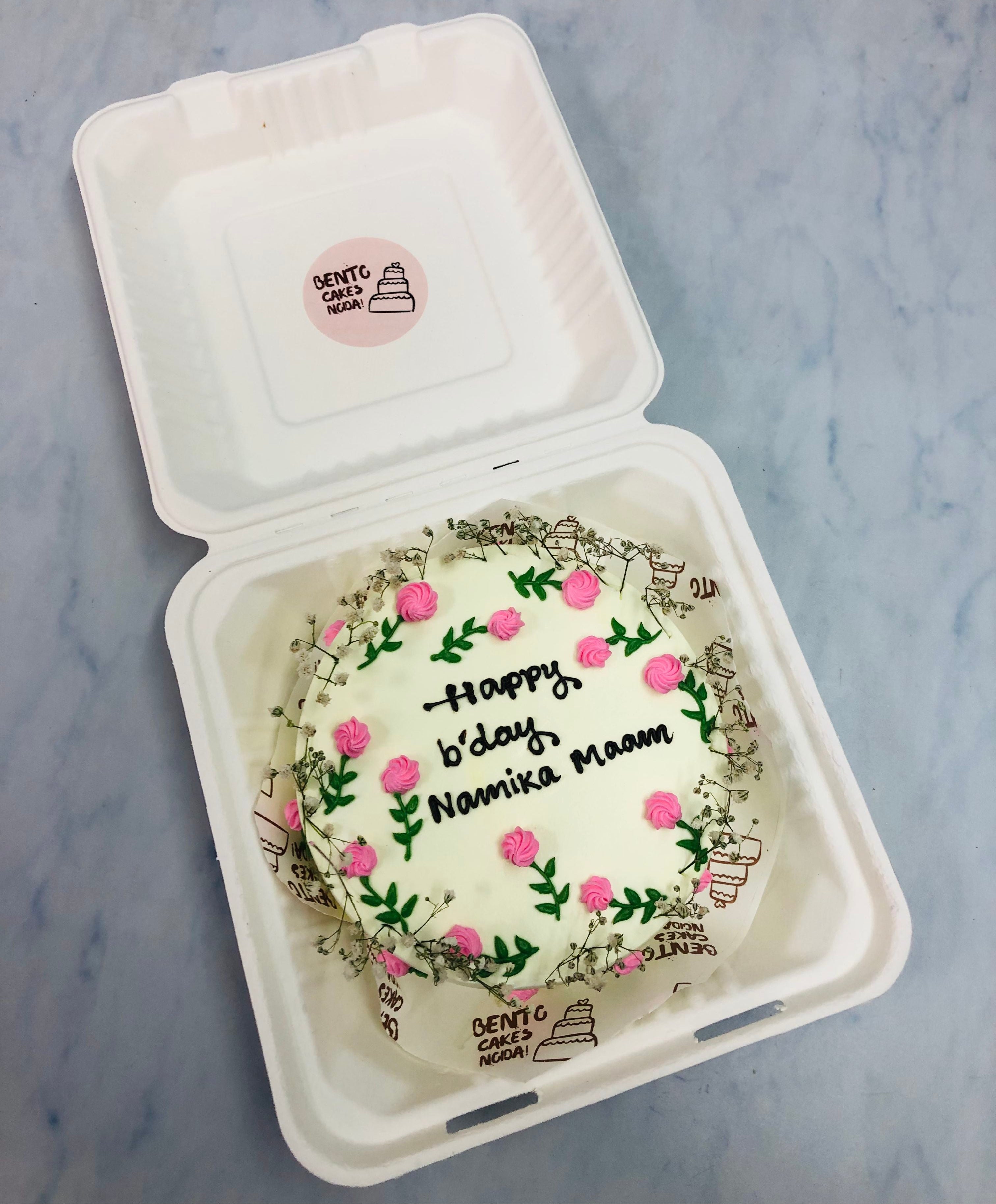 A white bento cake is decorated with pink floral design with green leaves for birthday.
