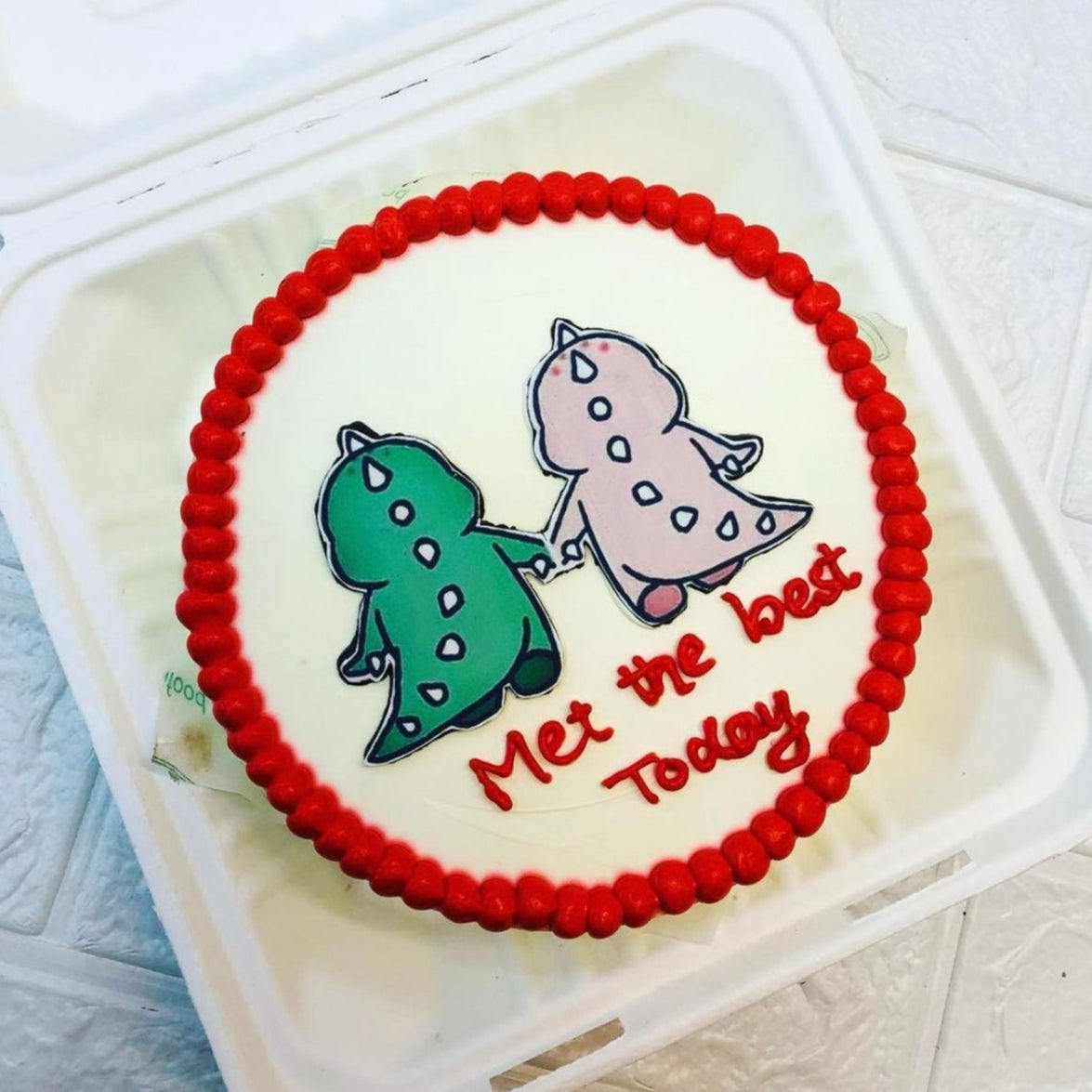 A delightful cake featuring two playful dinosaurs, beautifully presented in a bento box.