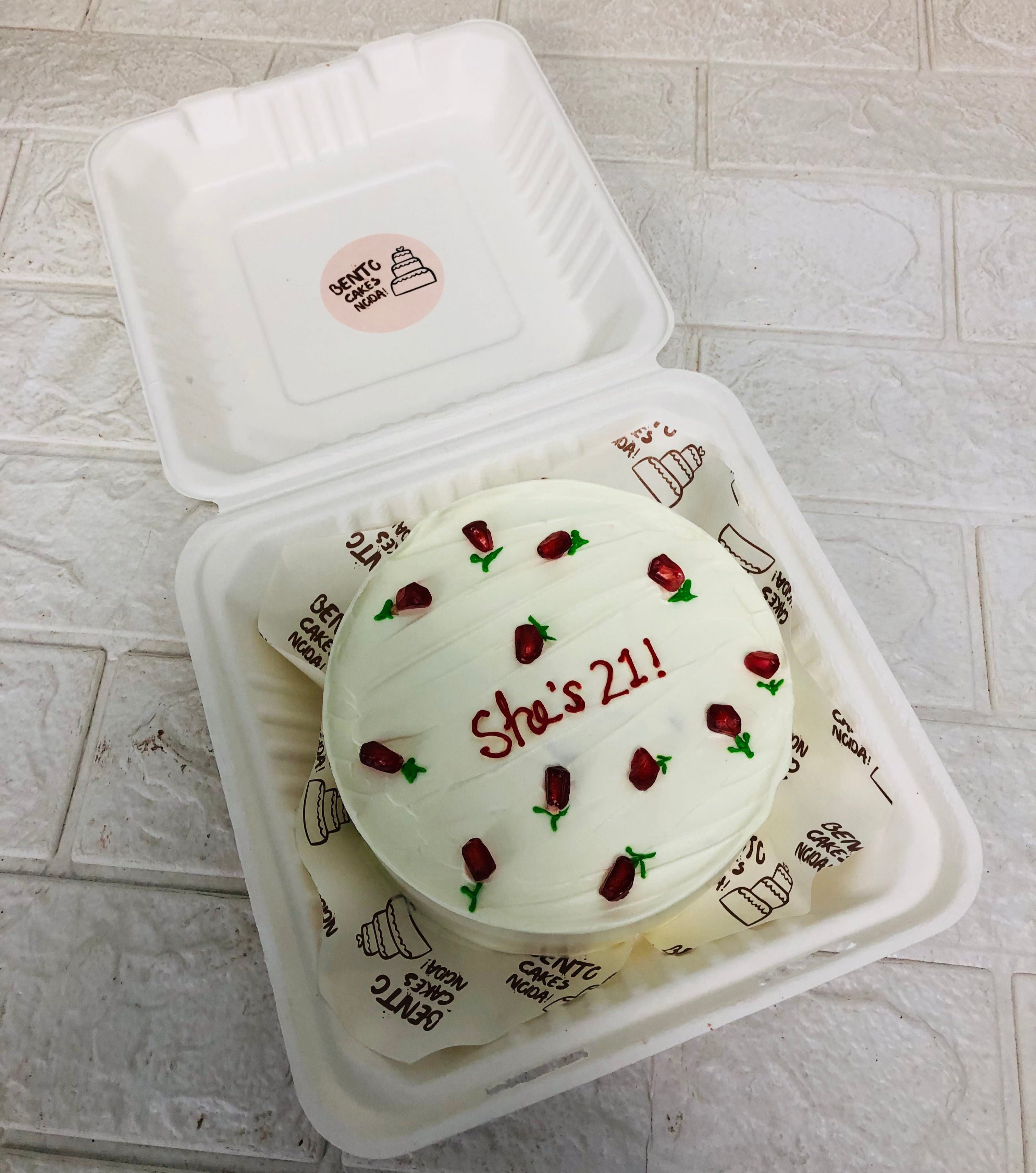 A white bento cake is designed with pomegronate seeds used like floral for 21st birthday of a girl.