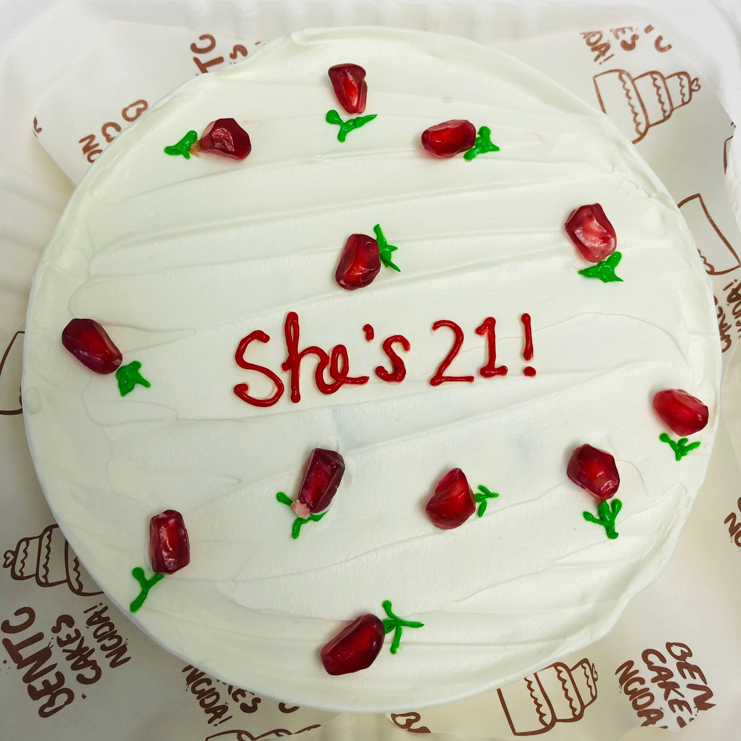 A white bento cake is designed with pomegronates seeds used like floral for 21st birthday of a girl.