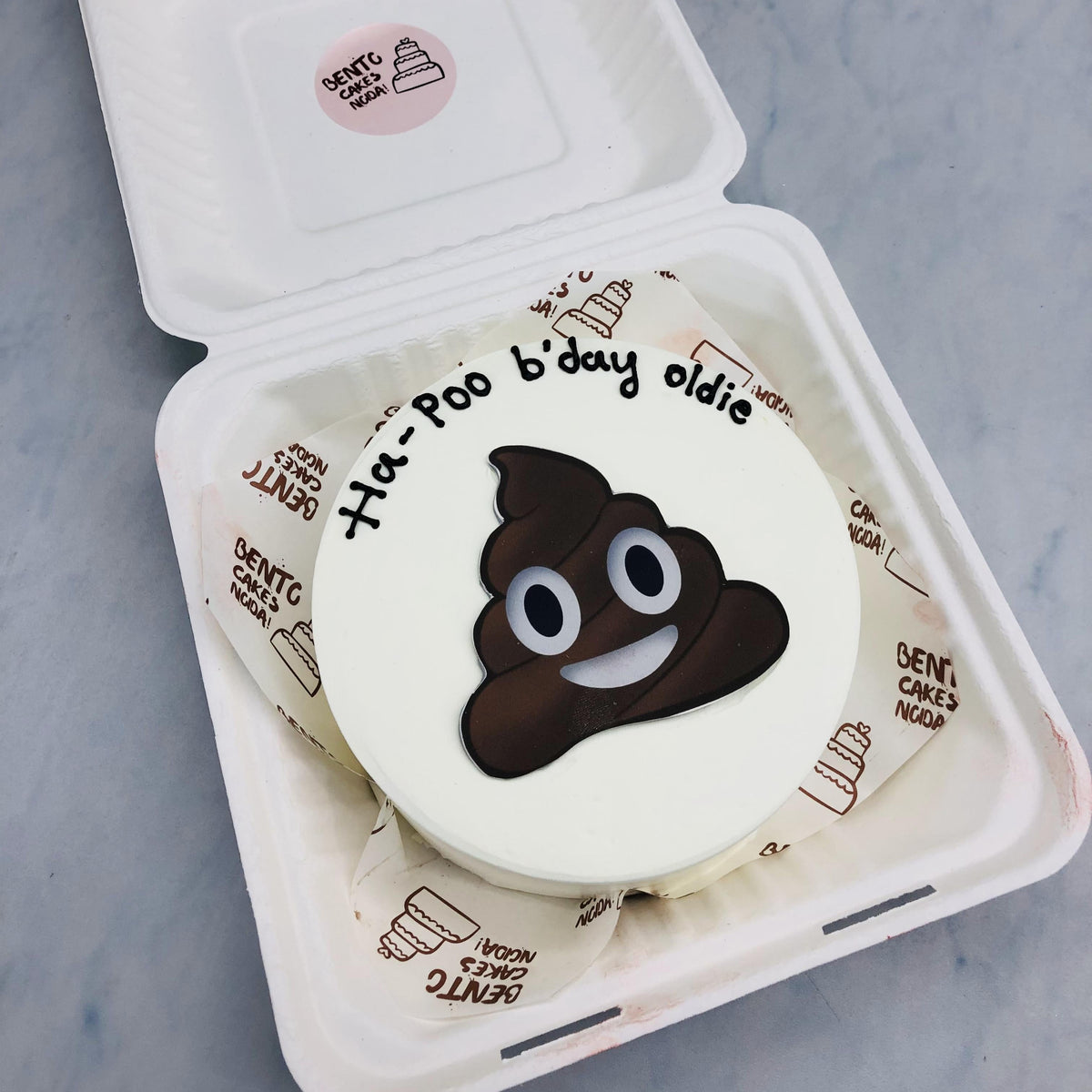 A white bento cake with poop design print.