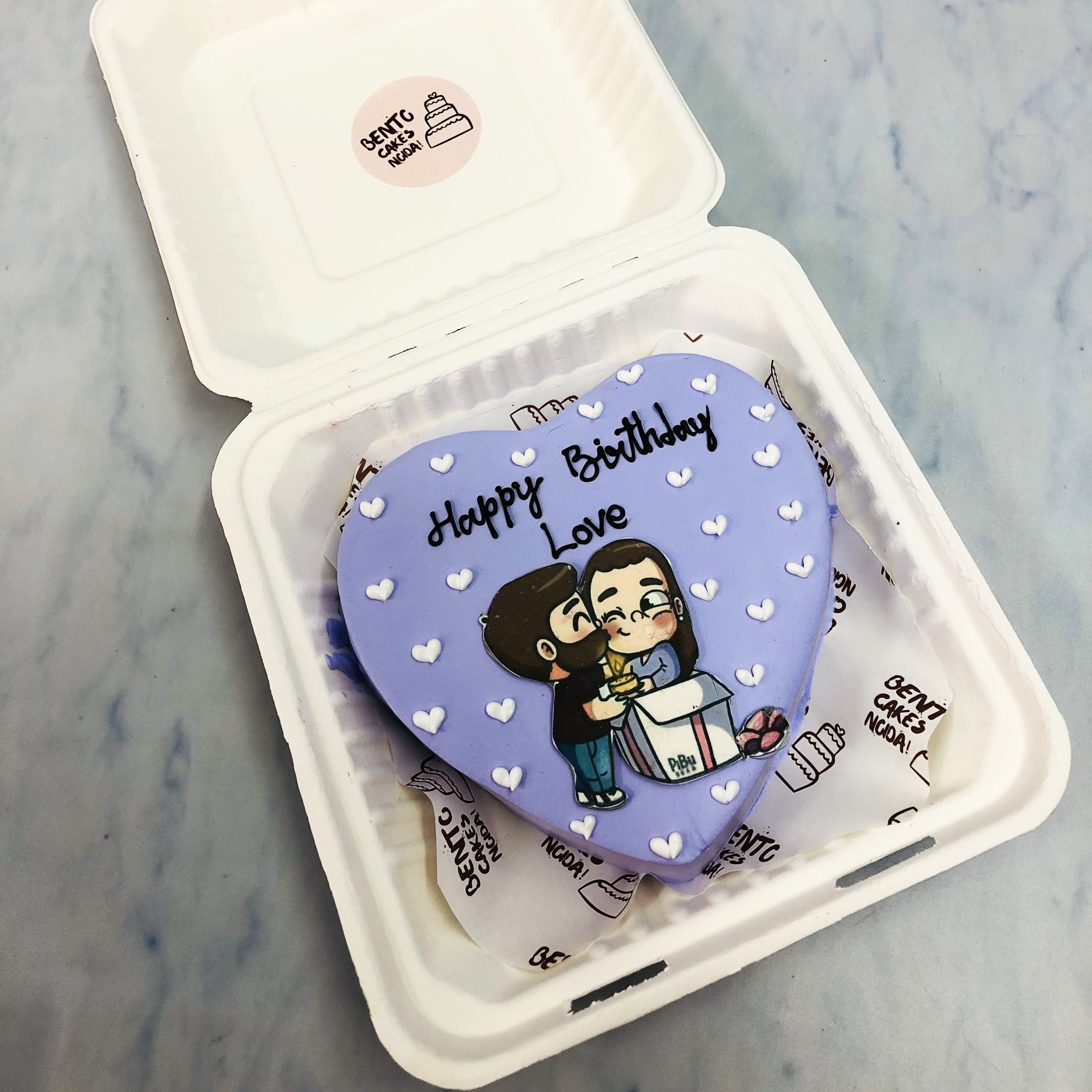 A pretty blue heart shape cake with a kissing couple sticker on it with little white hearts on it.