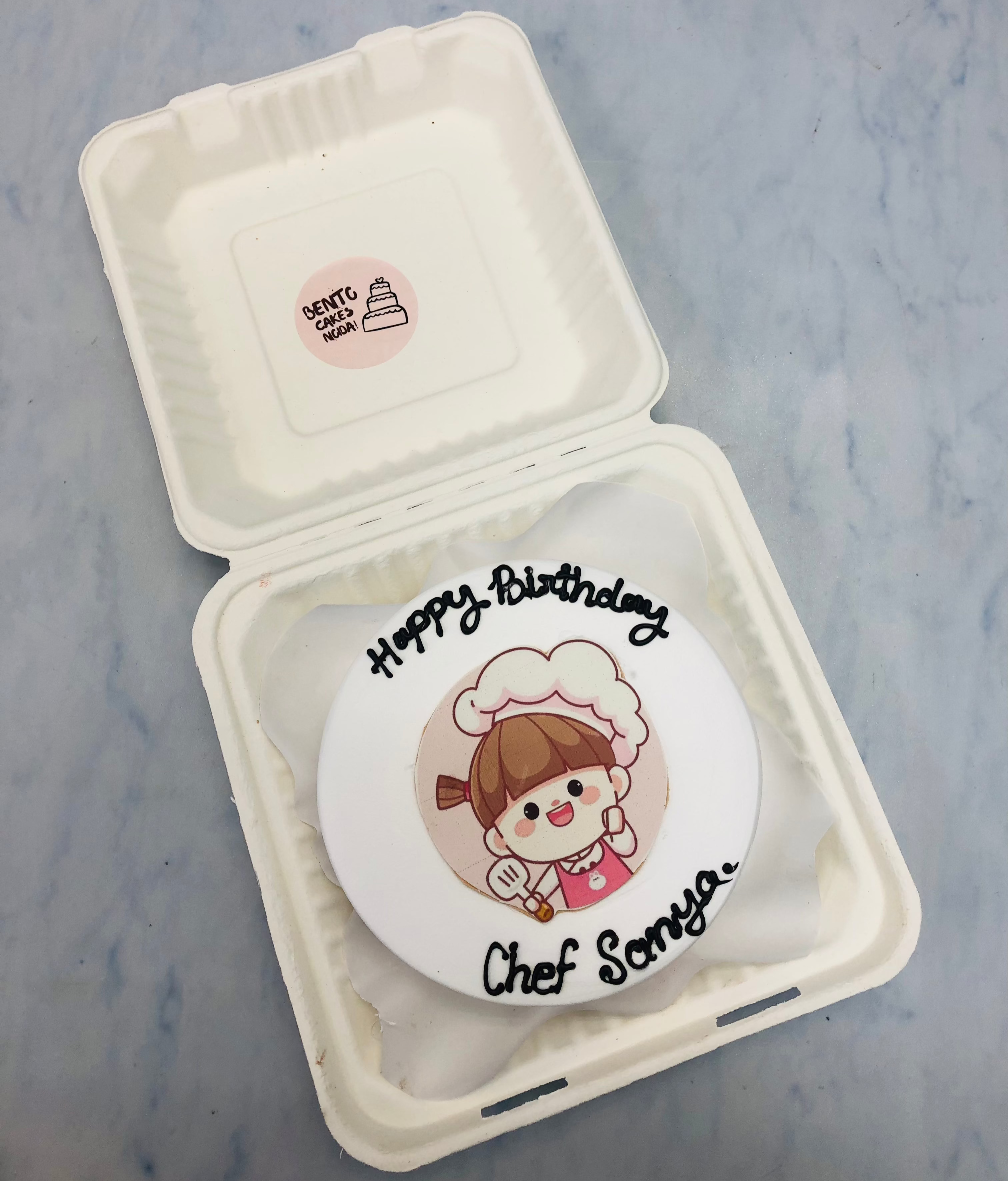 A white bento cake with a chef girl's print and designed for her birthday.