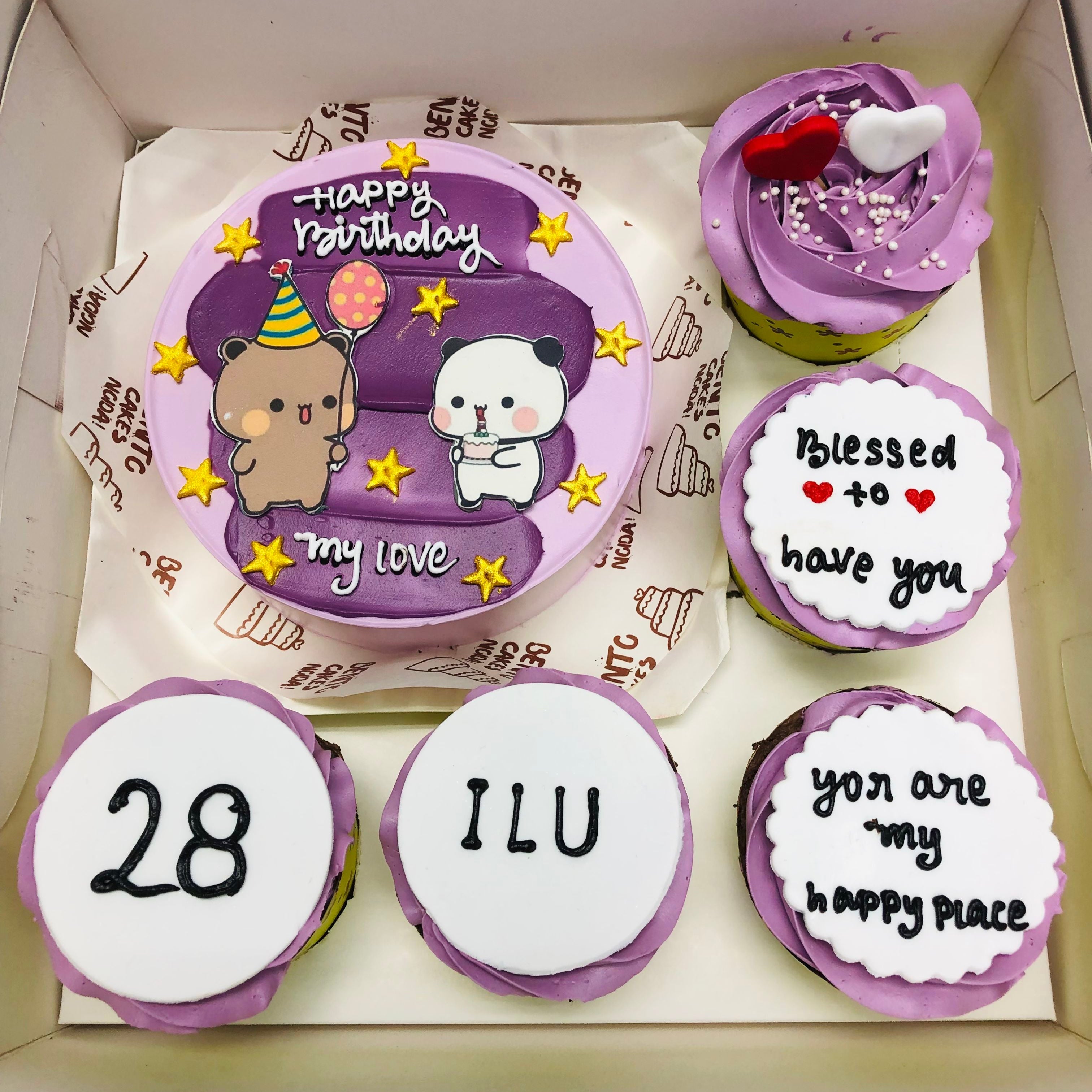 A boxed set of a purple-themed birthday cake and five cupcakes, each with unique decorations and messages. The cake features cute bear and panda characters with the text 'Happy Birthday my love'.