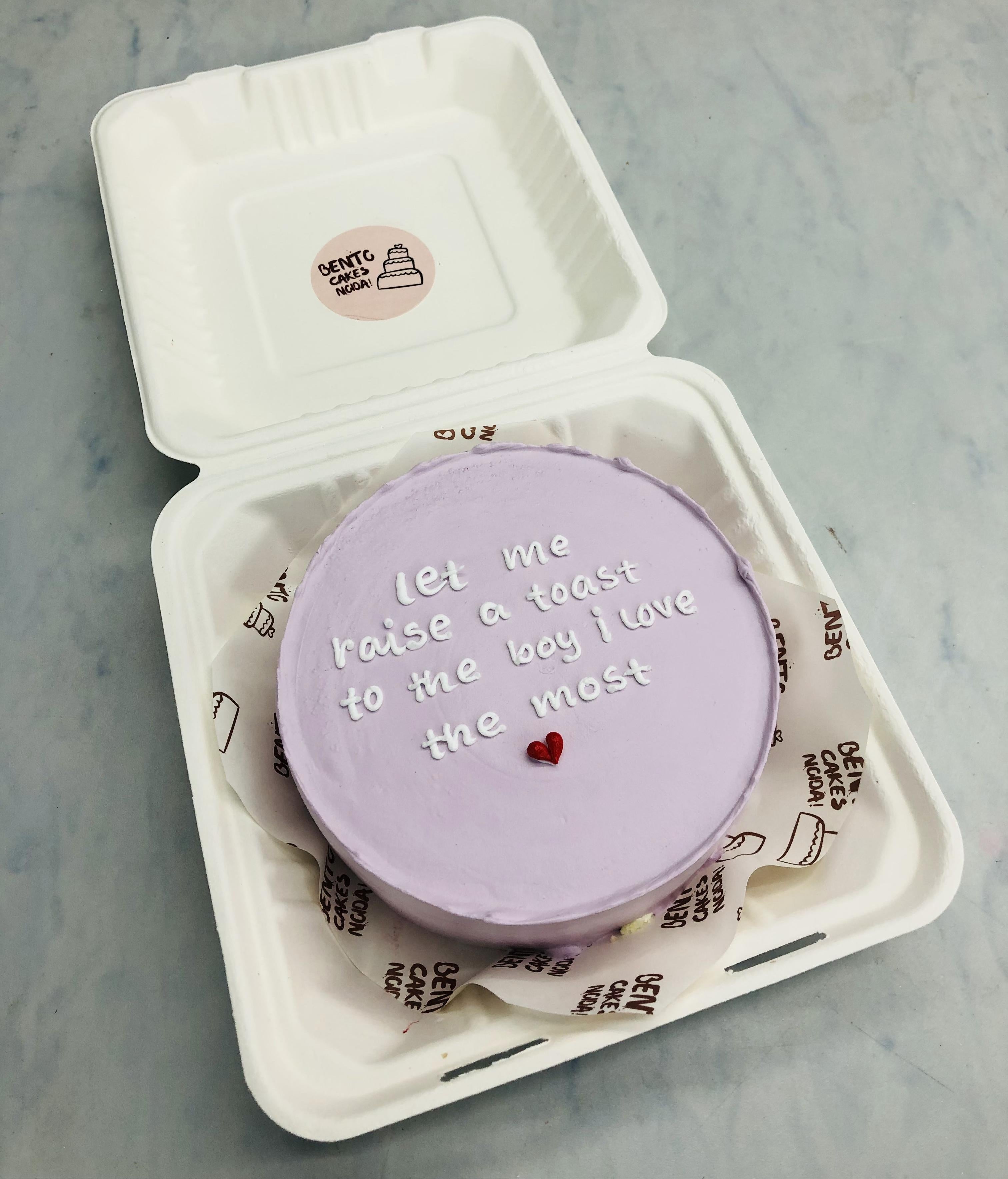 A light purple bento cake having a loving text written with white icing ith a cute heat design.