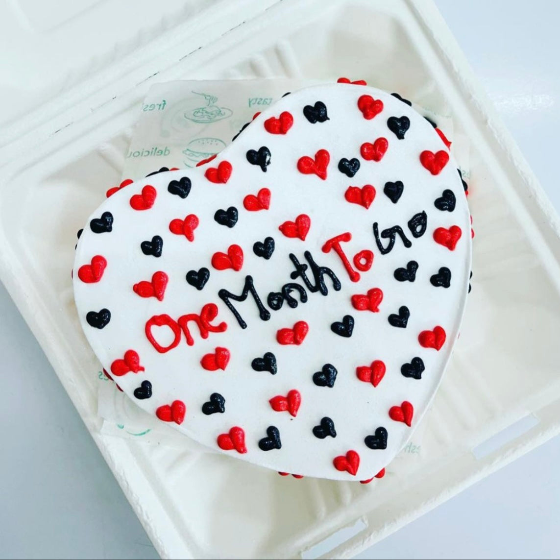 A heart-shaped cake adorned with red and black hearts, symbolizing love and celebration.