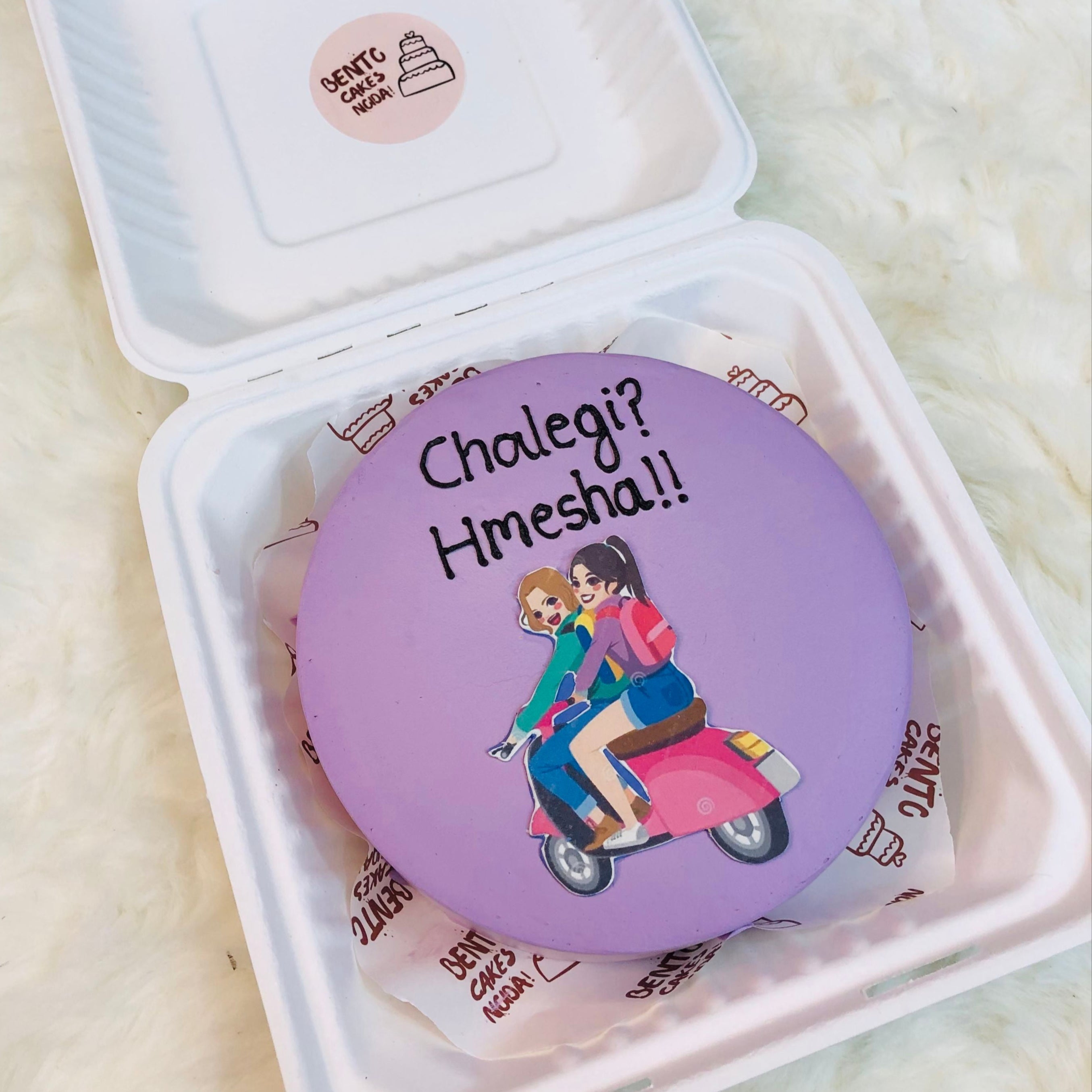 A bento box displaying a sticker that complements its color scheme, also in purple with a test adorn "Chalegi Hmesha!"