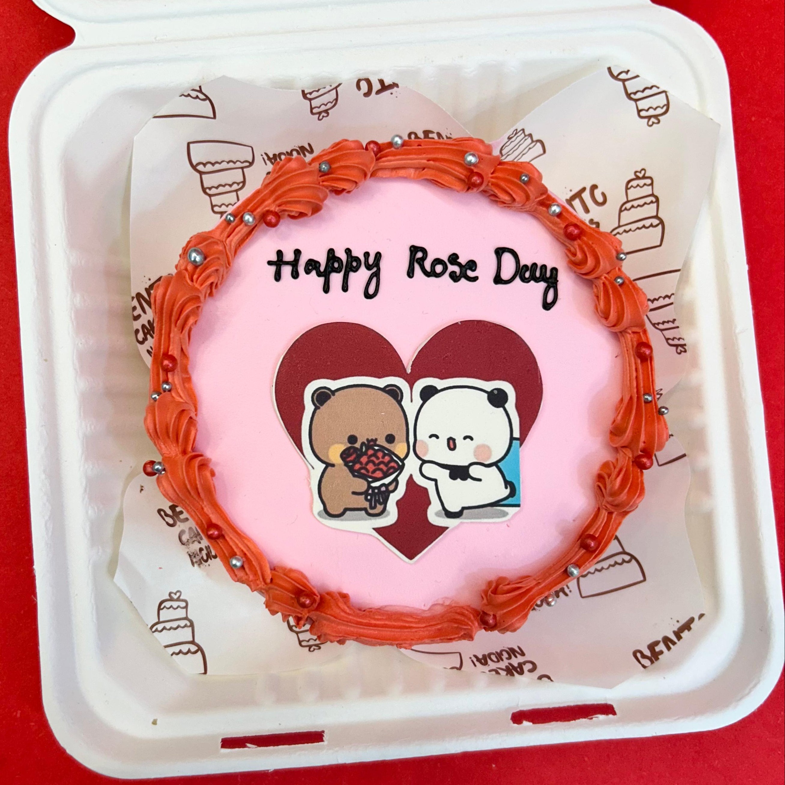 A delightful cake with a heart design, accompanied by the Bubu Dudu cartoon character from front view, ideal for Rose Day festivities.