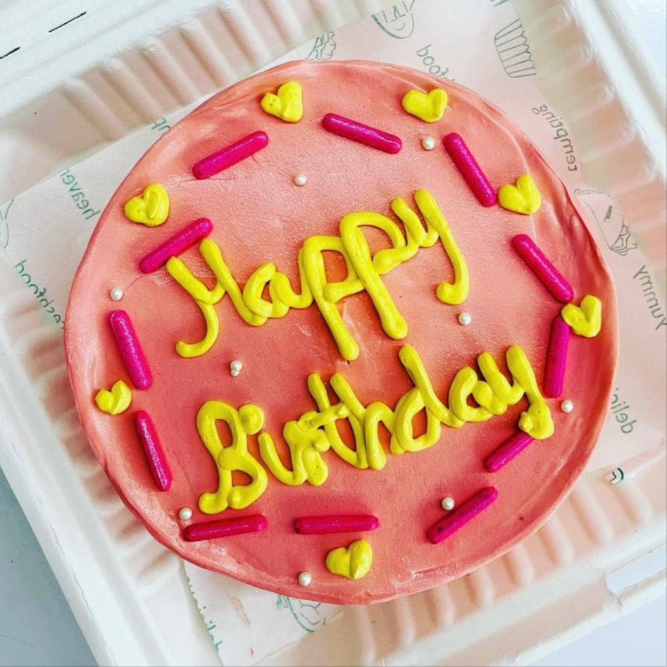 A heart-shaped cake displayed in a soft foam container, showcasing its delightful design and vibrant colors.