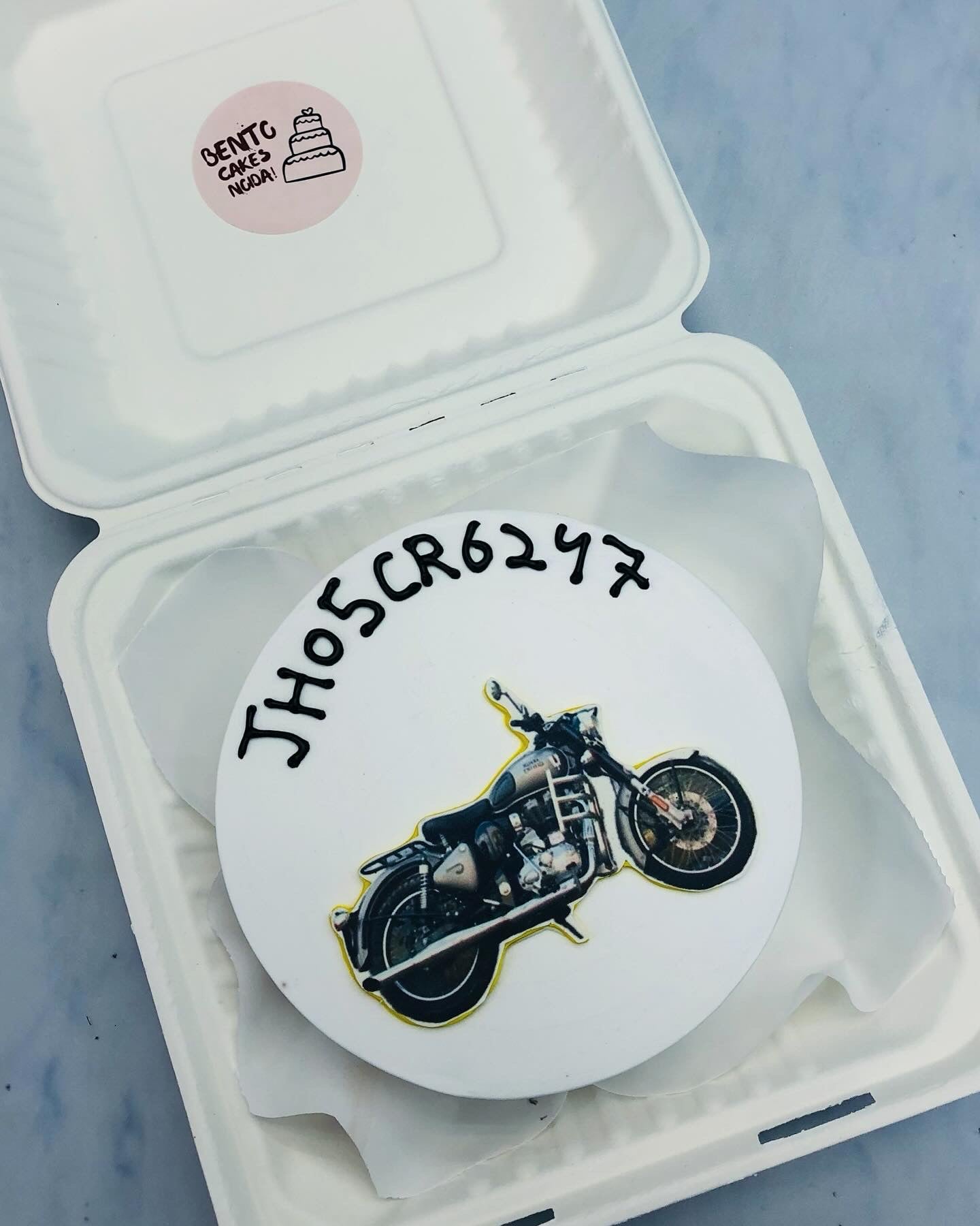 A white bento cake with Royal Enfiend bike print.