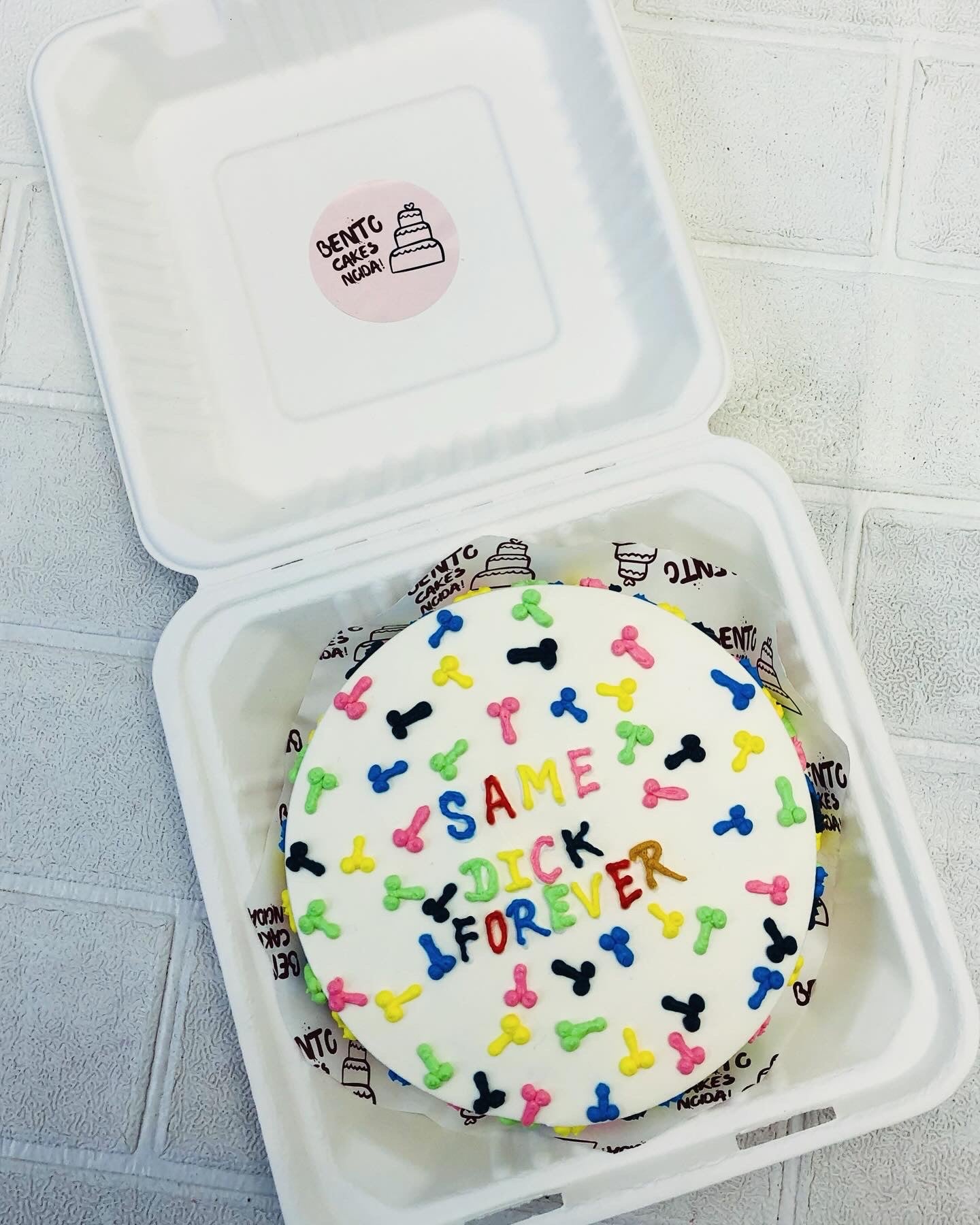 A white bento cake designed with colorful dick designs and a text "SAME DICK FOREVER" written with colorful text.