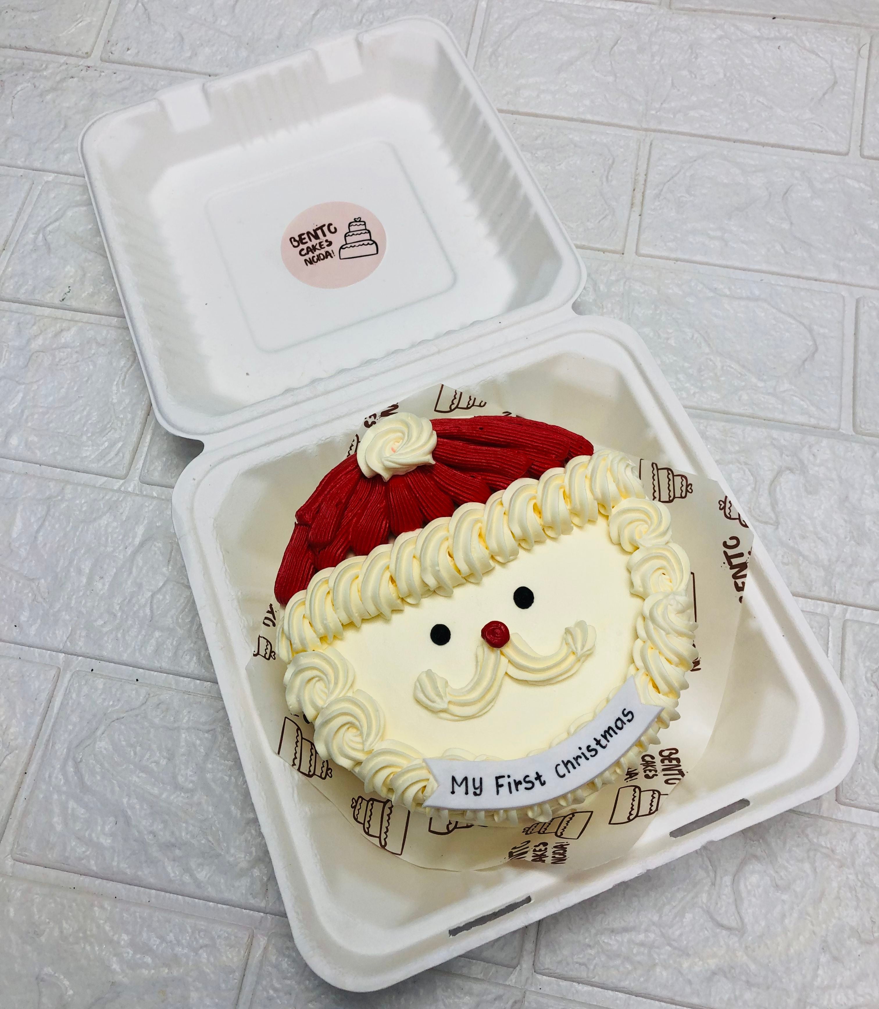 An offwhite bento cake is is designed for christmas festival with a santa clause face wearing a red cap.