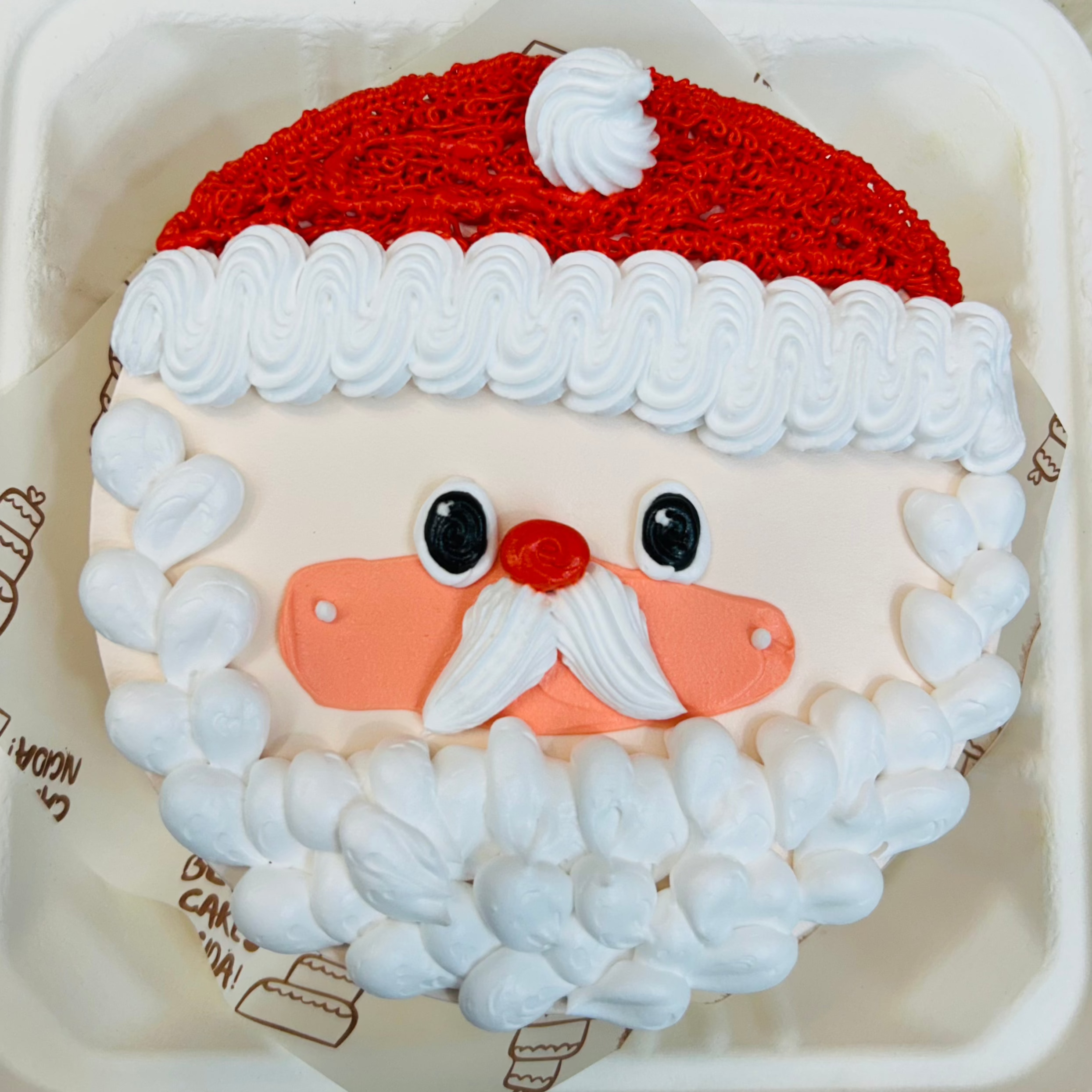 A peach color bento cake with a santa clause face design and weaing a red cap for Christmas occasion.