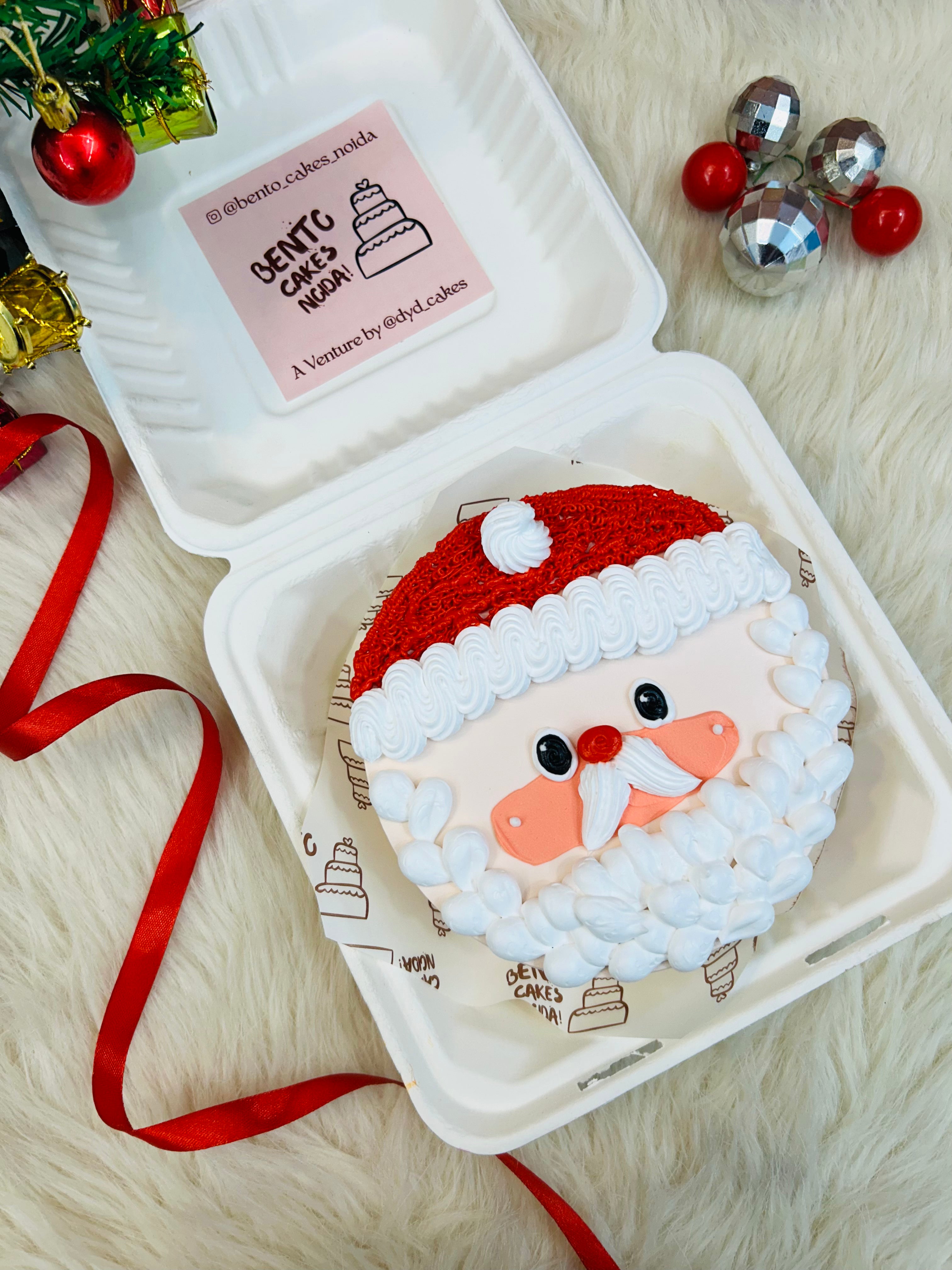 A peach color bento cake with a santa clause face design and weaing a red cap for Christmas occasion.