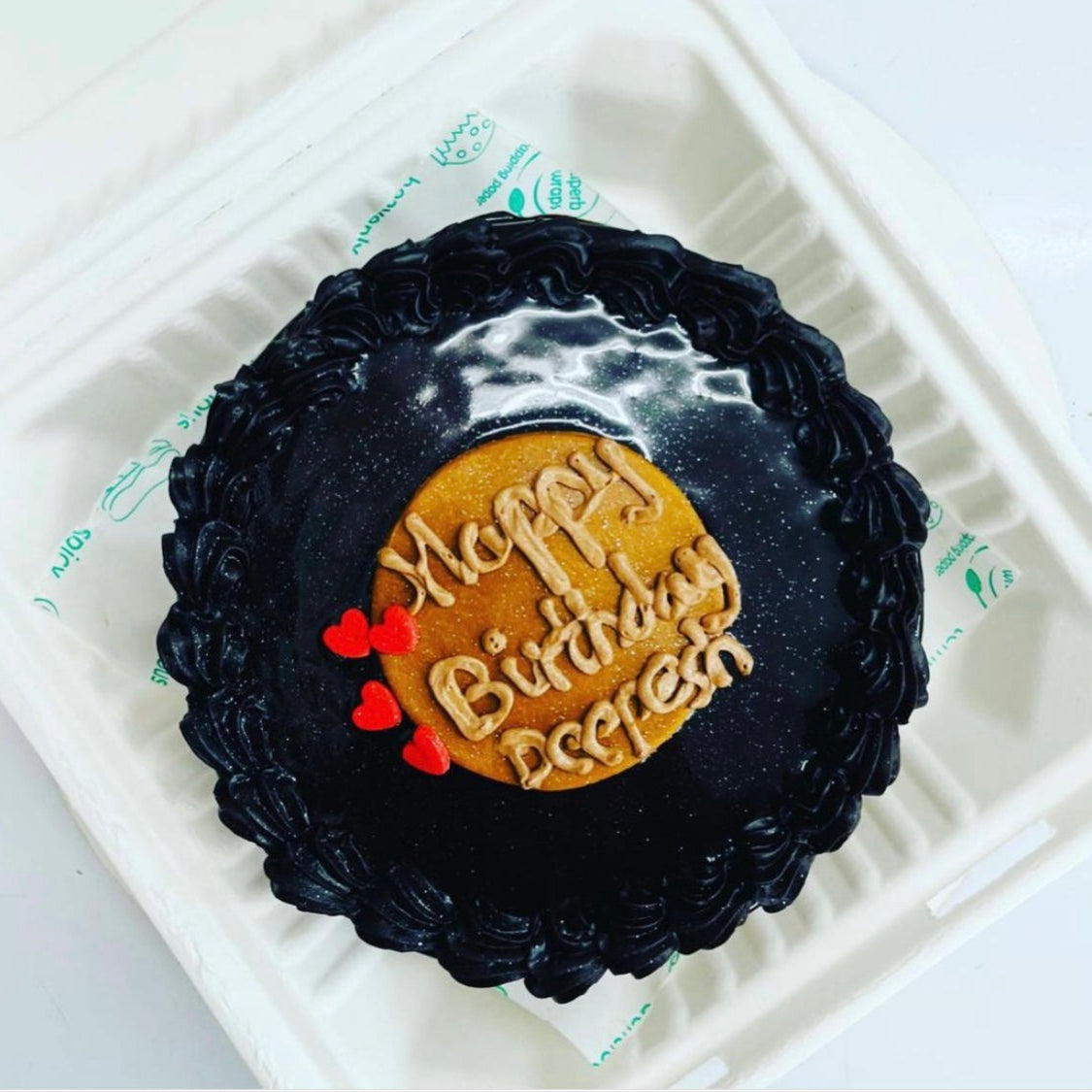 A beautifully designed black and brown birthday cake featuring the words "Happy Birthday" prominently displayed.