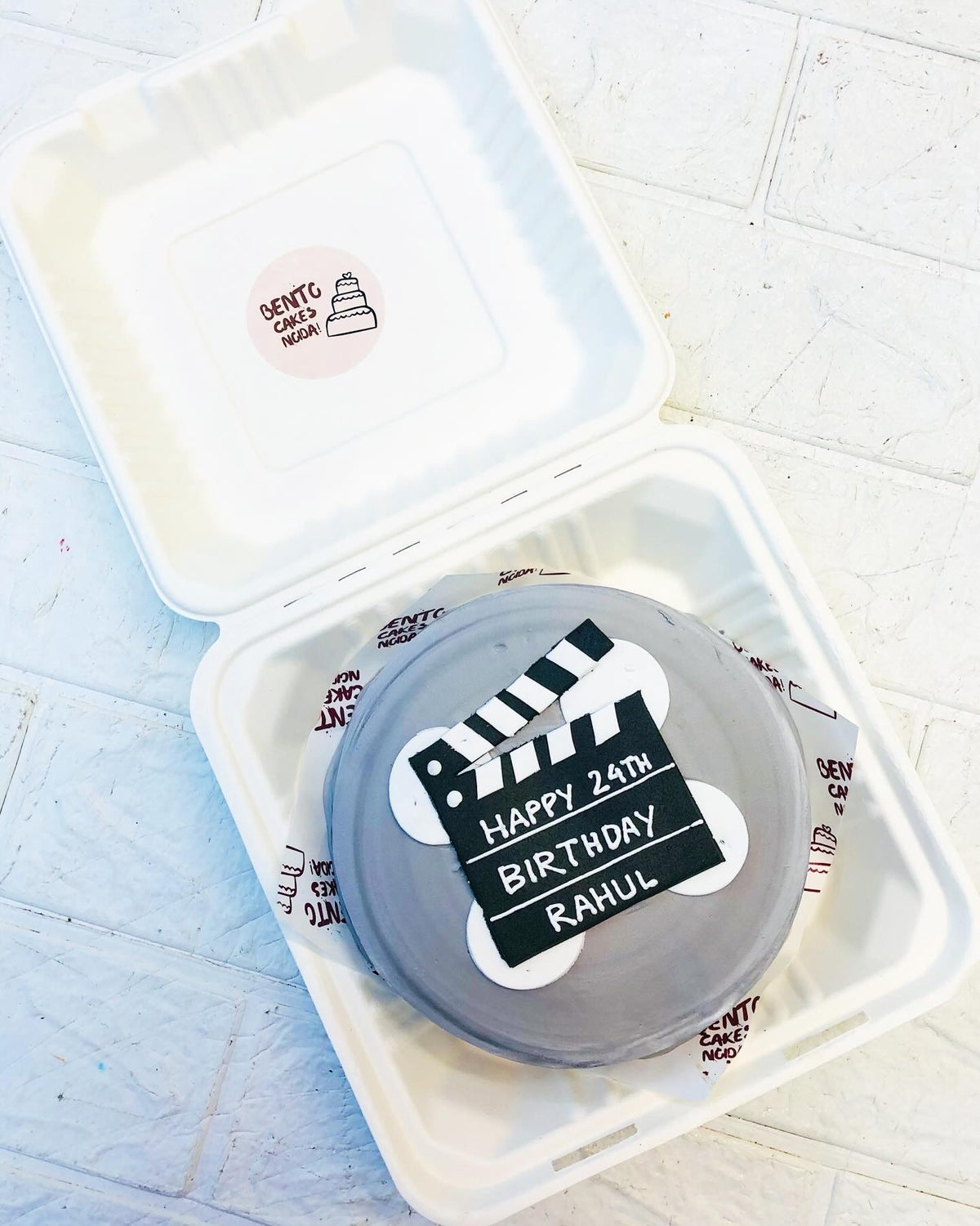 A grey bento cake is designed for a movie shoot theme for a shoot taker's birthday.
