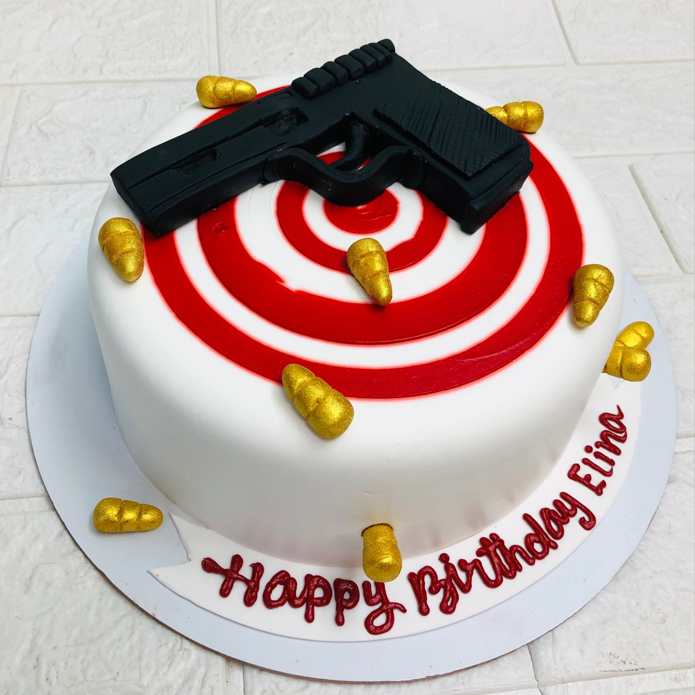 A creatively designed cake adorned with a gun and a target, representing a bold and striking visual concept.