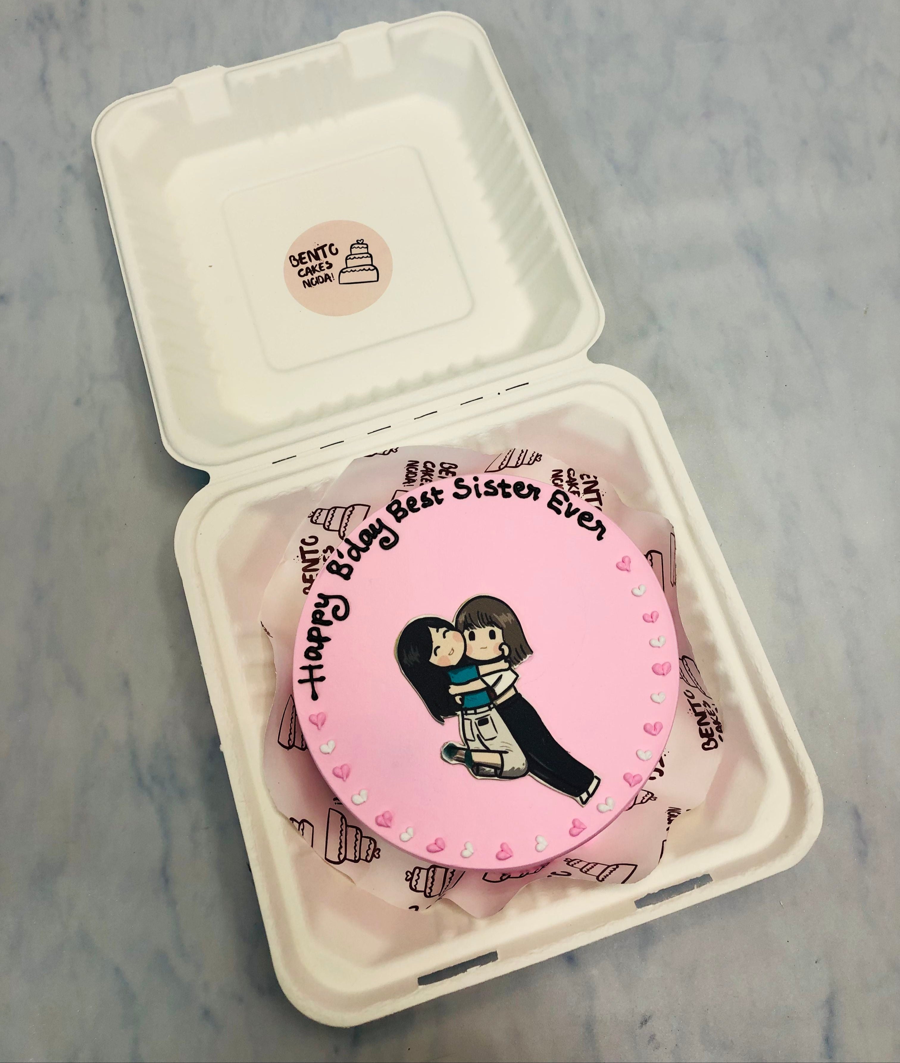 A light pink bento cake showing 2 sisters love.