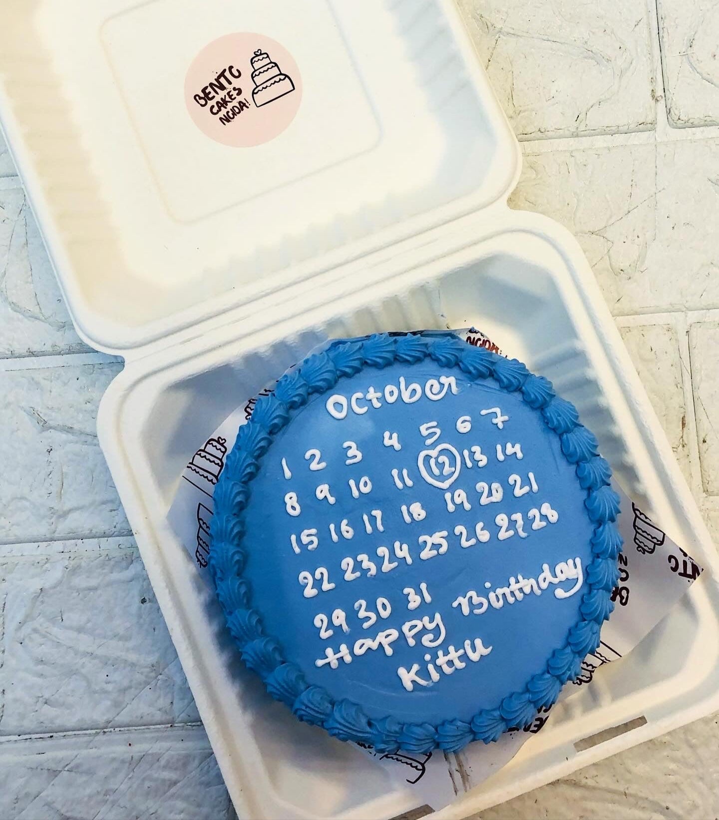 A sky blue bento cake having white calendar design for birthday celebration.