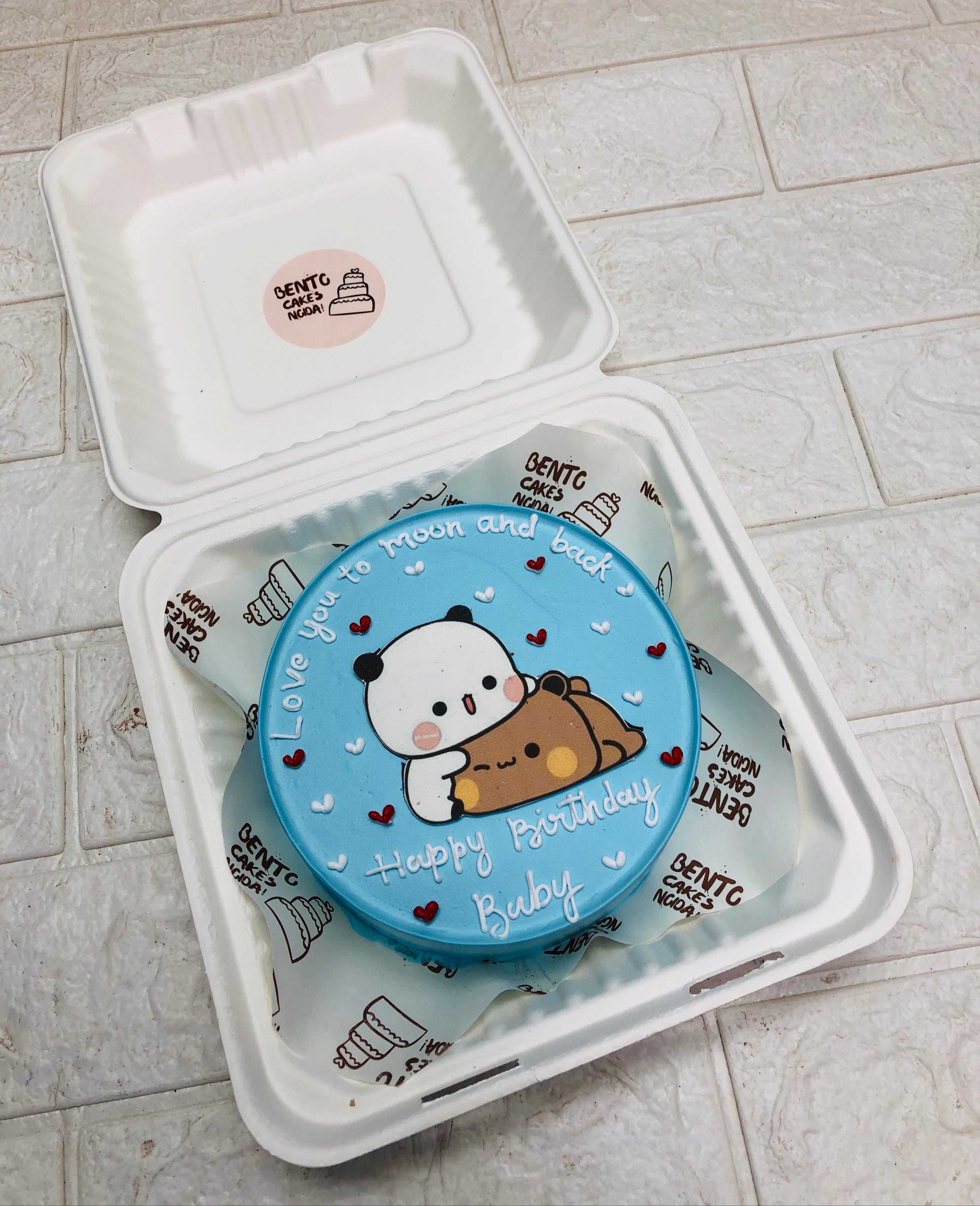 A shiney blue bento cake with sleepy bubu dudu character with red and white hearts design.
