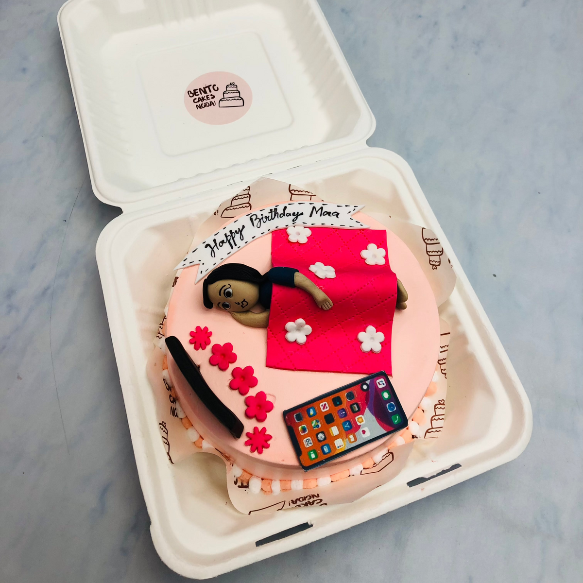 A fondant design sleepy mom bento cake with her gadgets.
