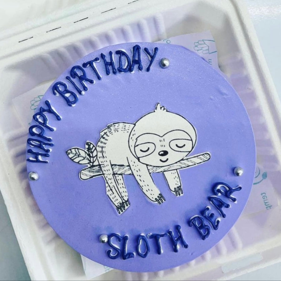 A charming birthday cake with a sloth perched on it, decorated with bright frosting and playful accents for a joyful occasion.