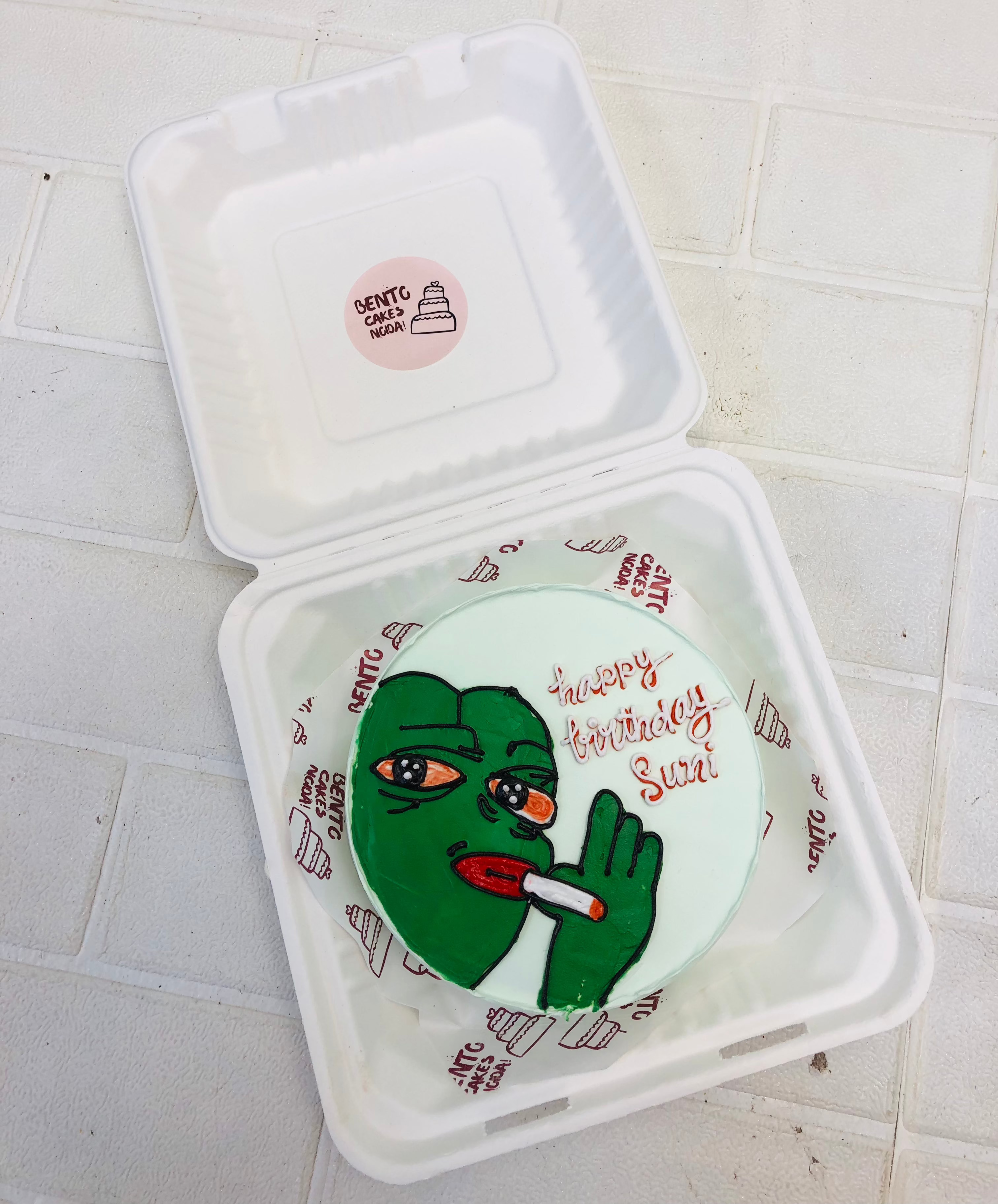 A smoker green cartoon design on a white bento cake for birthday.