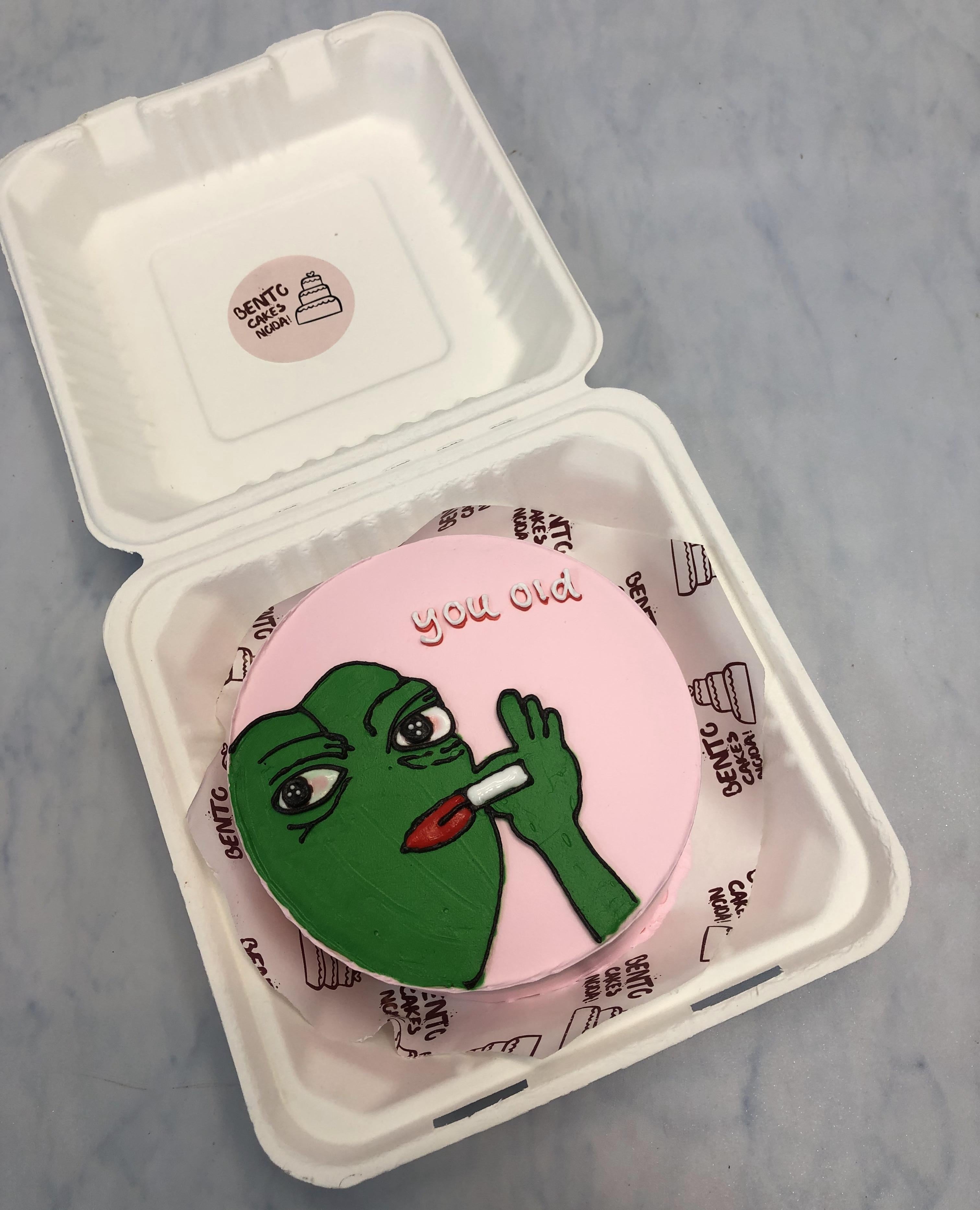 Smoker green frog theme on baby pink bento cake with "you old" text on it.