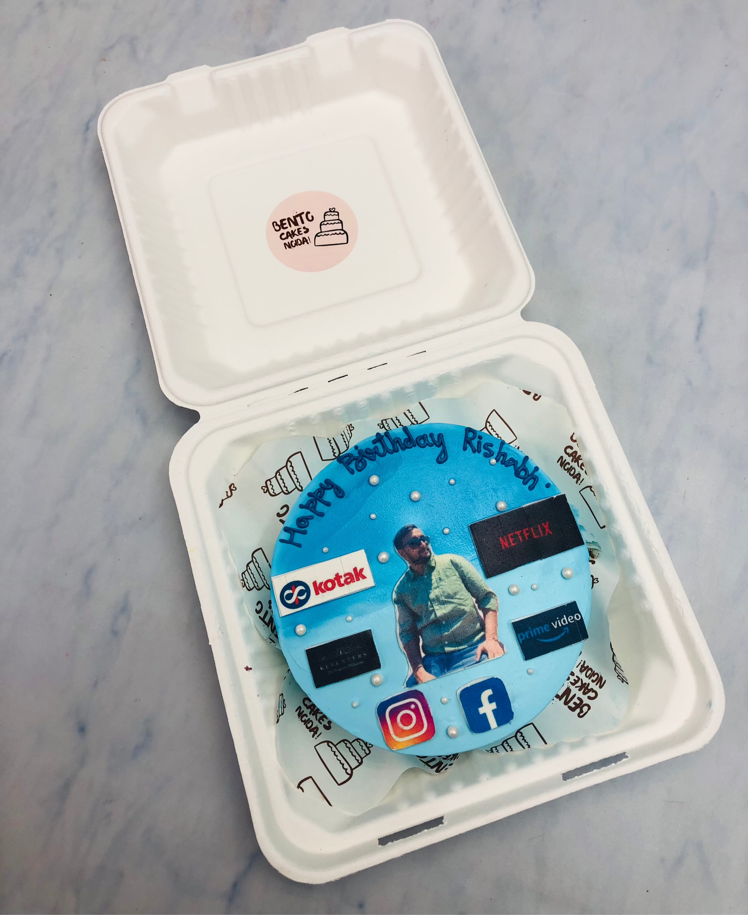 A light blue bento cake with social media addicter guy image.
