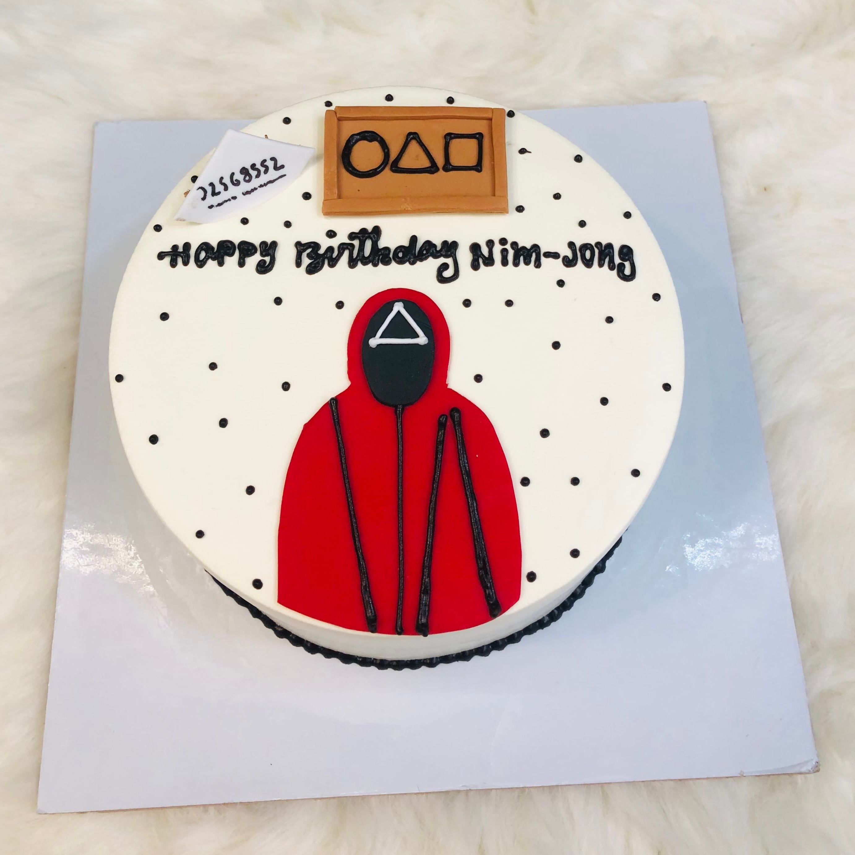 A birthday cake adorned with a red hoodie and a playful black and white polka dot pattern visible from front view.