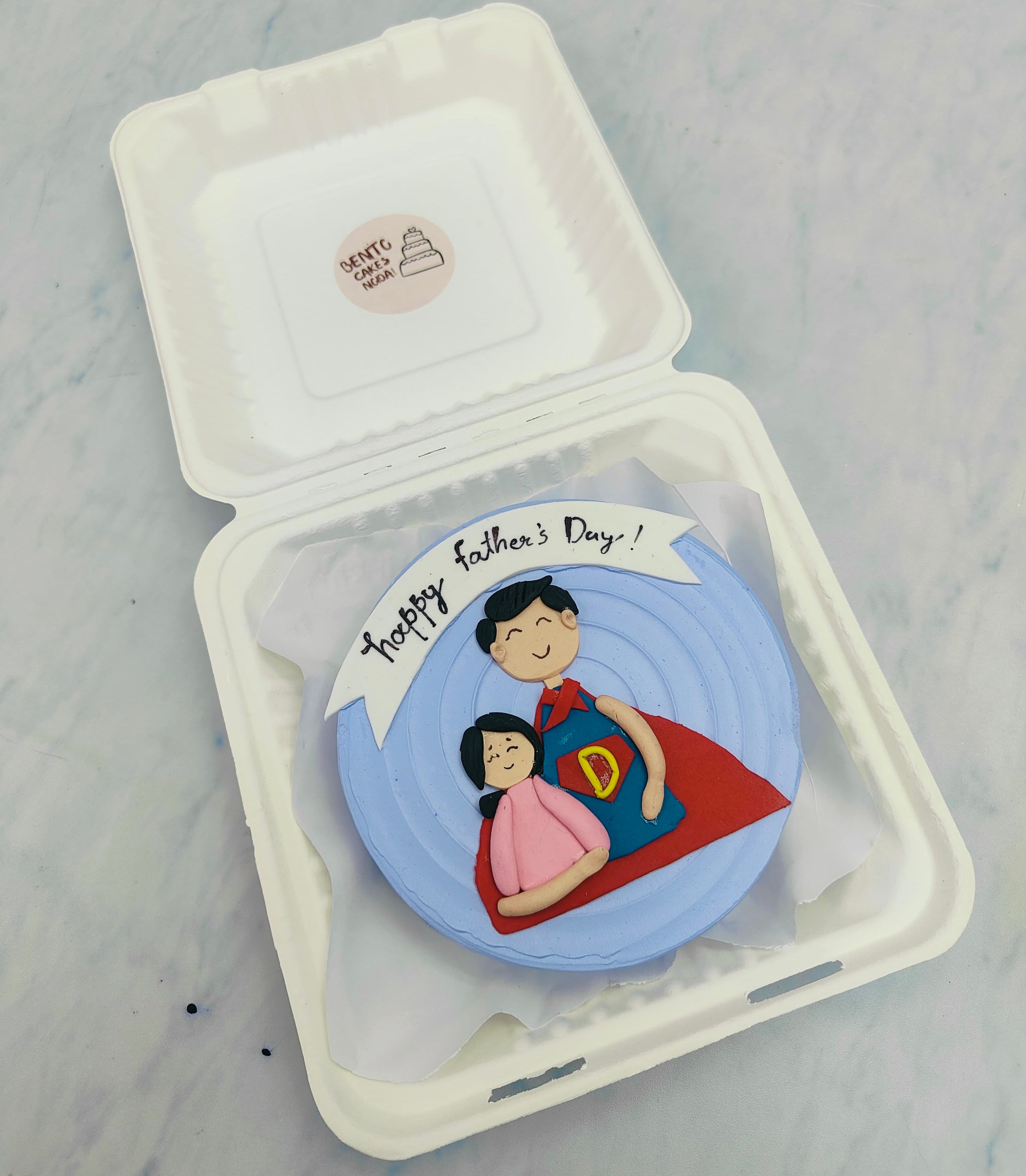 A blue bento cake having a girl wishing her fathers day celebration. with girl and father fondant design