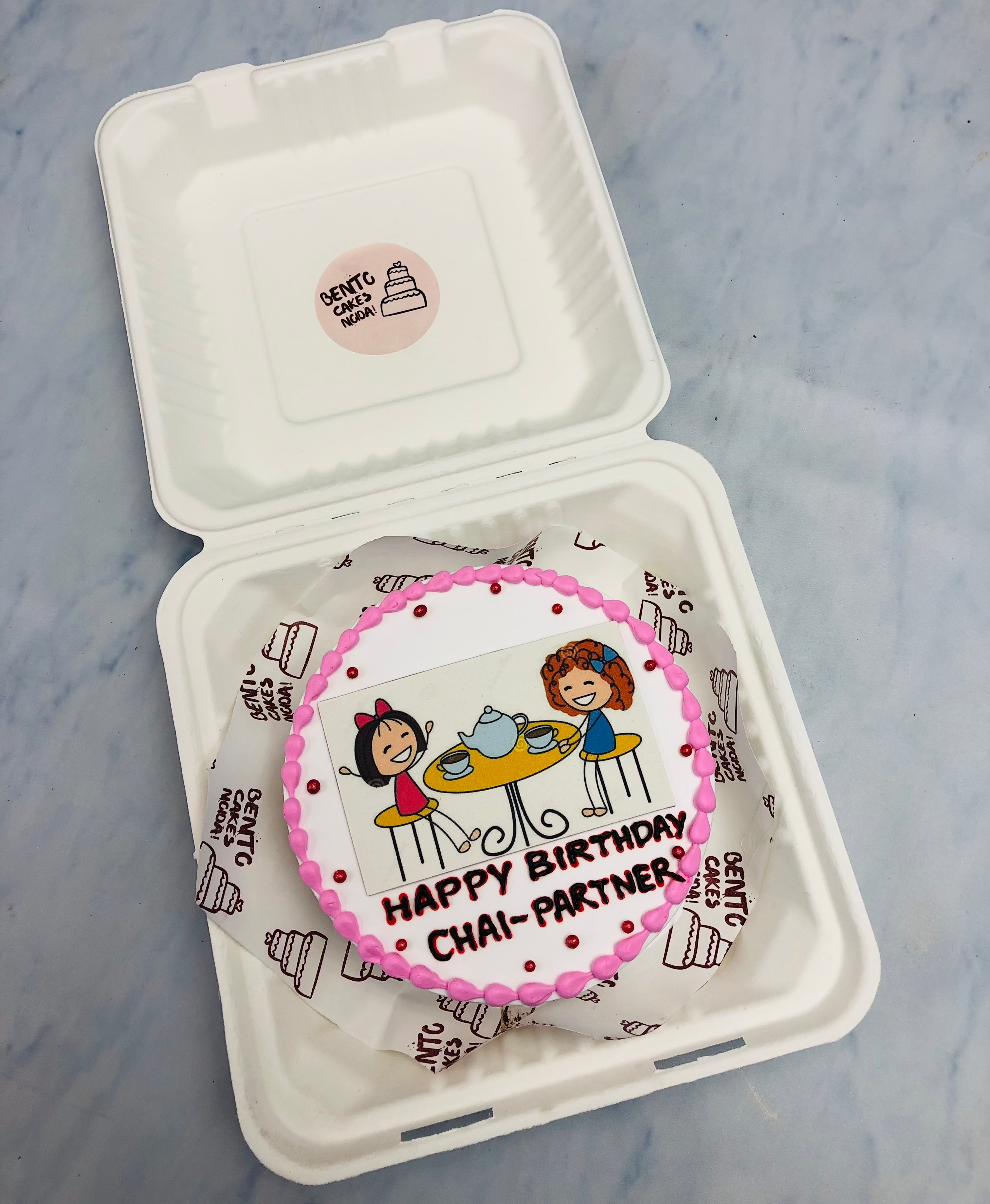 A white bento cake of 2 friends taking Tea together.