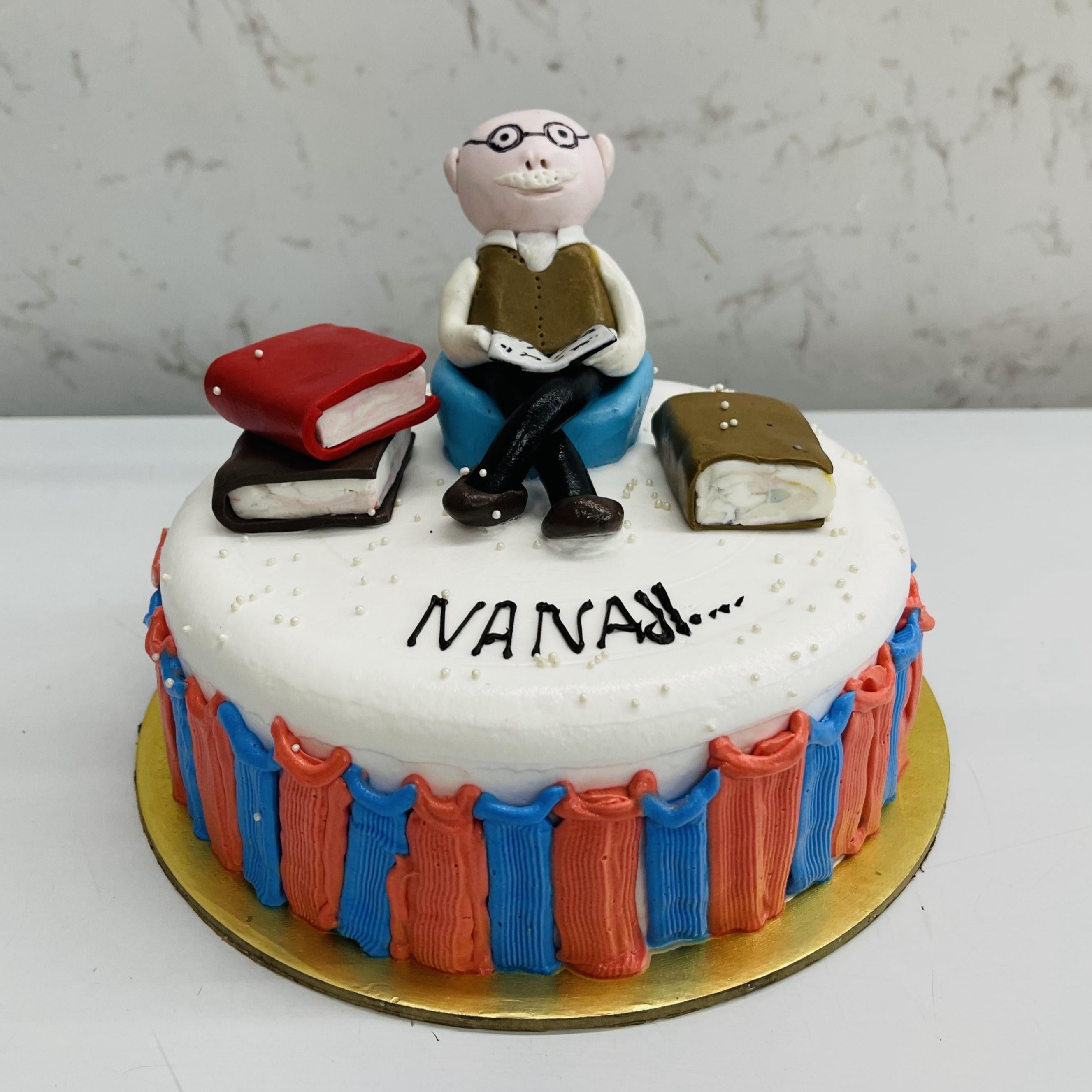 Beautifully designed cake for a teacher with a man sitting on cake and having lots of books.