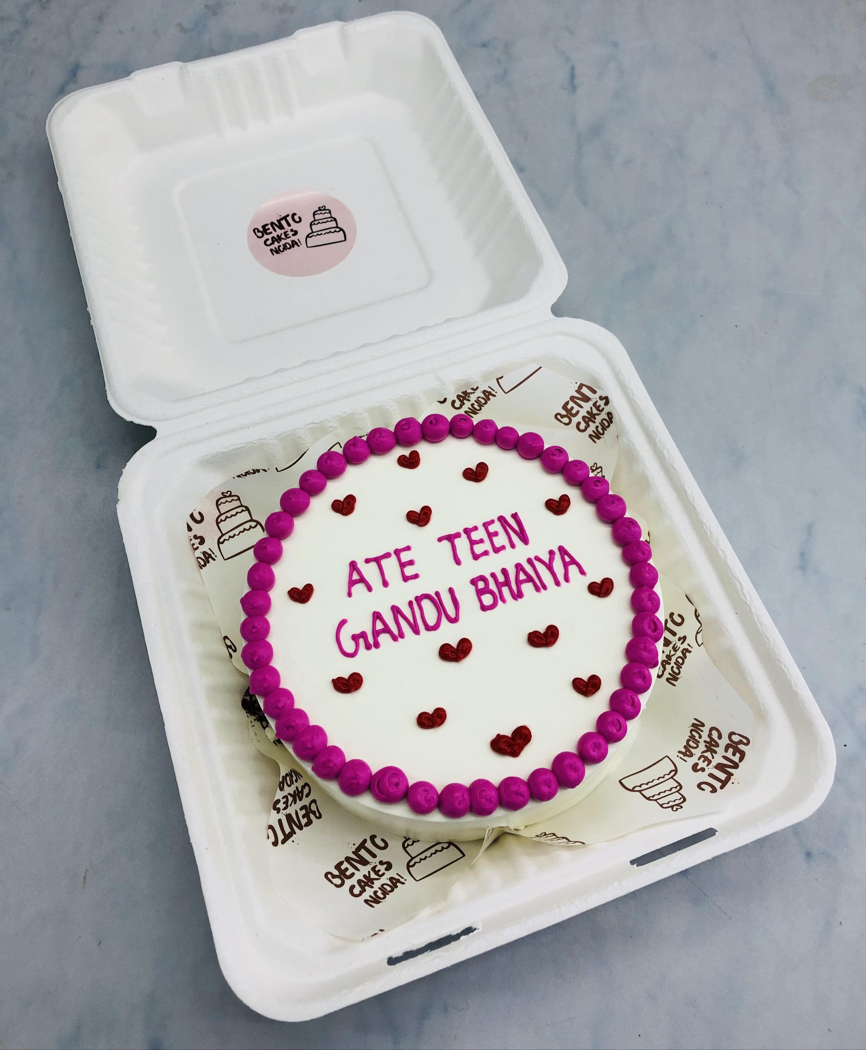 A white bento cake designed with pink dots on bounday and a text written with pink icing and filled with red hearts.