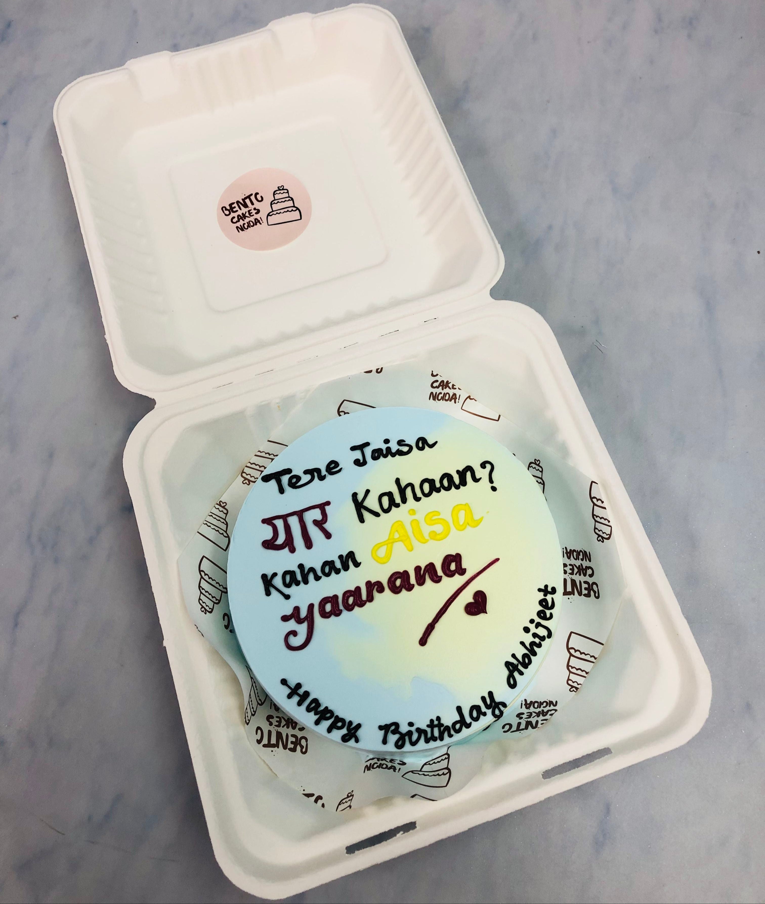 A light blue white bento cake with friendship text.