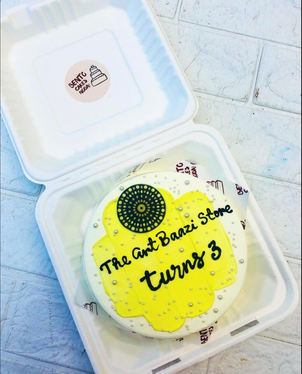 The Art Baazi Store Theme white Bento Cake with yellow shade on top.