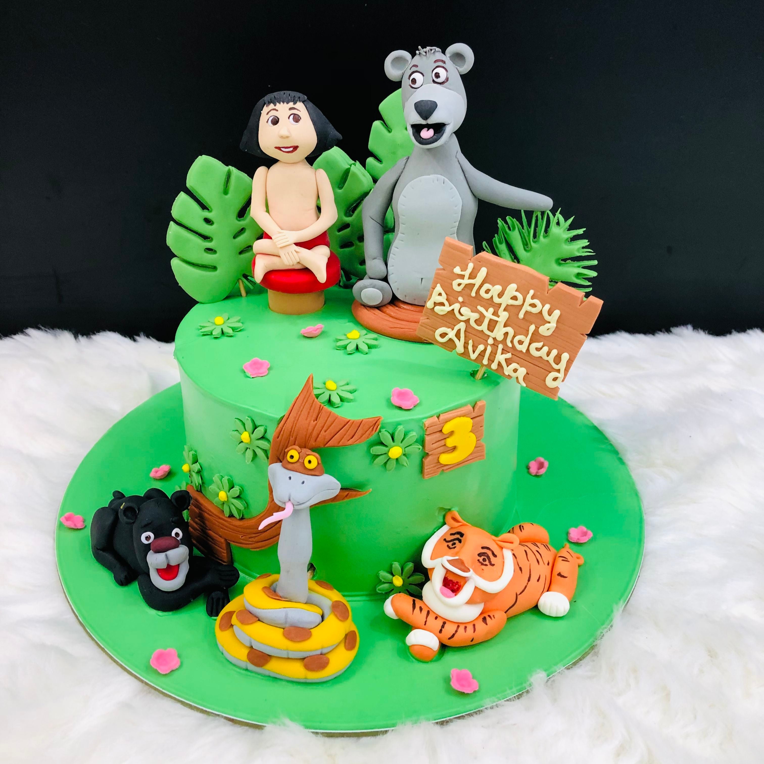 A jungle-themed cake featuring a bear and a tiger, adorned with vibrant foliage and playful decorations.