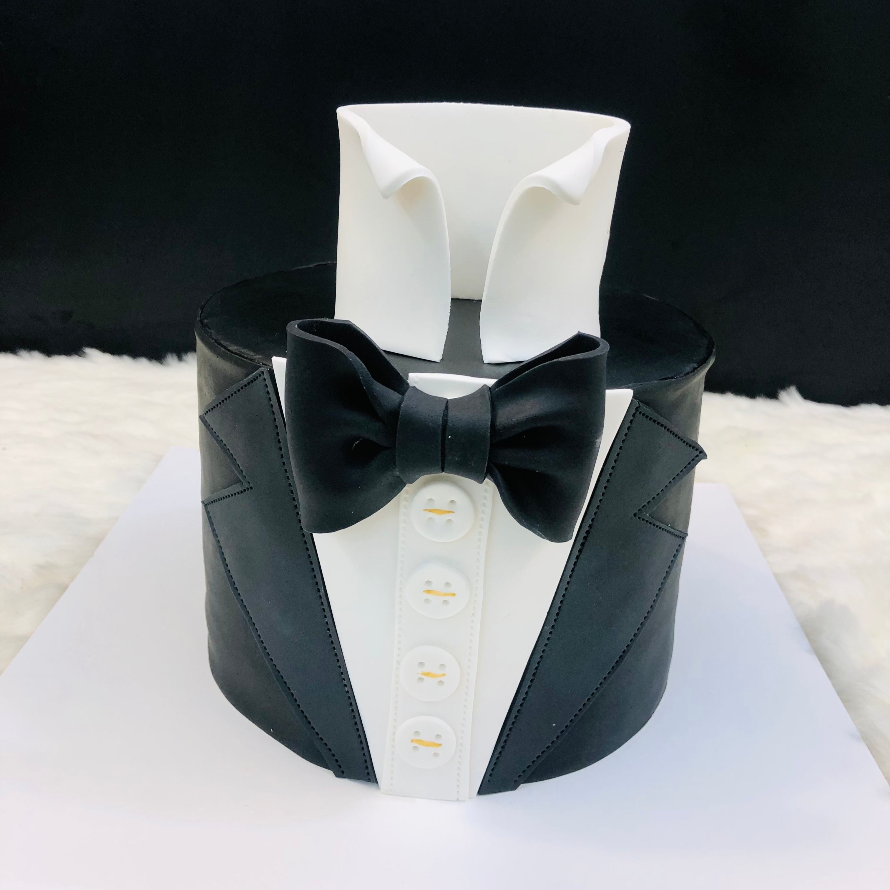 A stylish cake decorated with a tuxedo and bow tie, perfect for a formal celebration or special occasion.