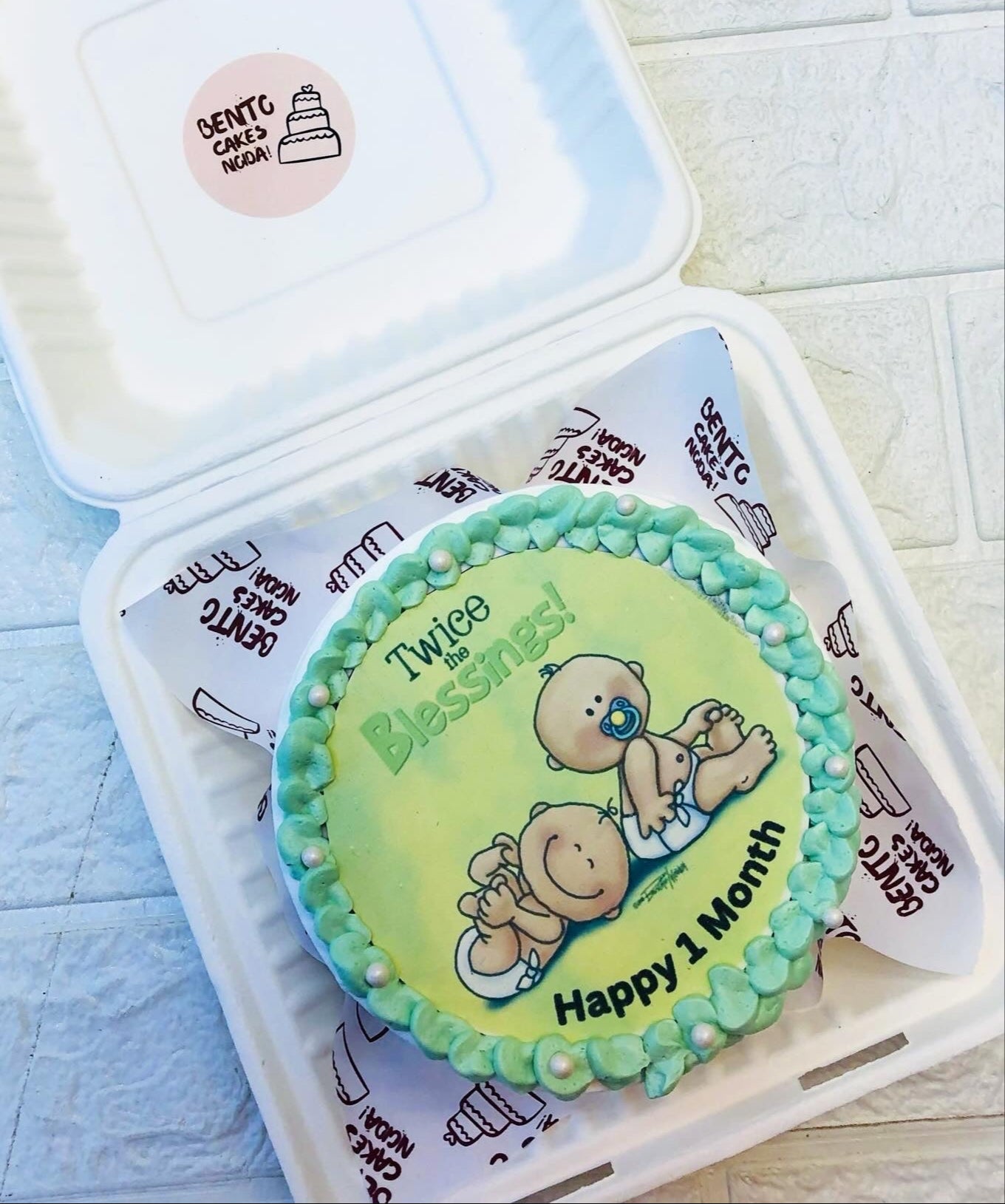 A white bento cake with twin baby cute print on it.