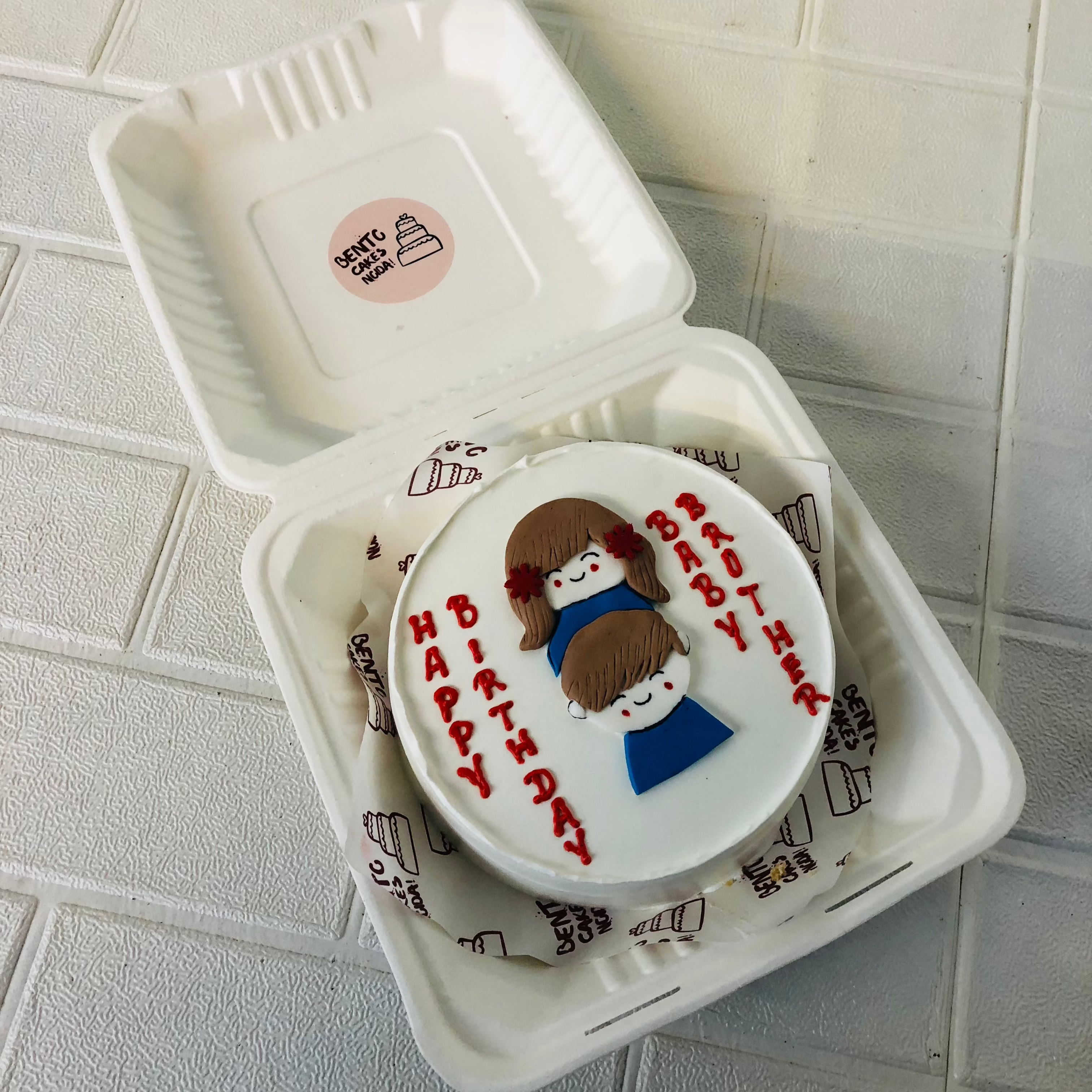 A white bento cake with fondant brother and sister's design.
