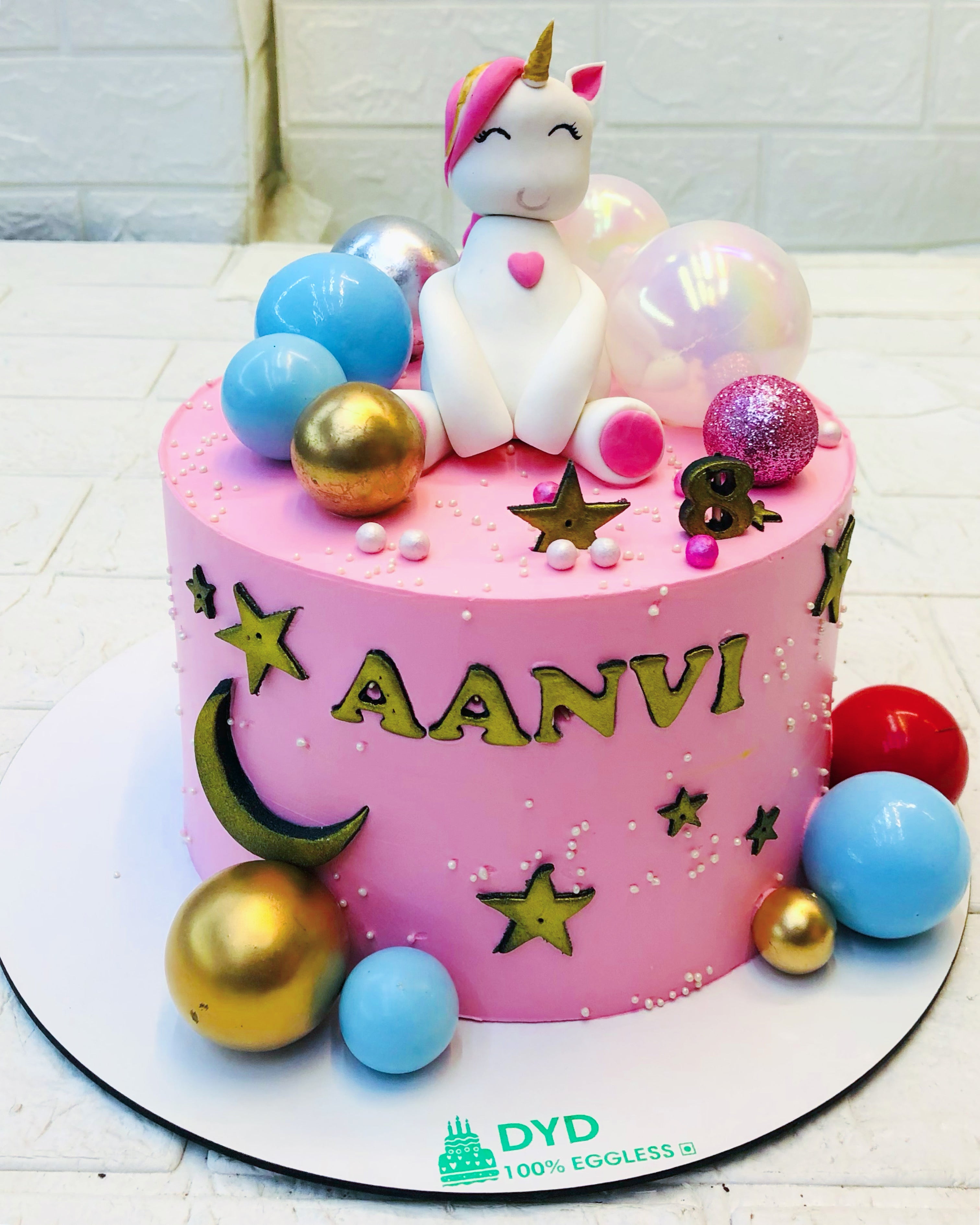 A pink cake topped with a whimsical unicorn and a vibrant rainbow, perfect for a magical celebration.