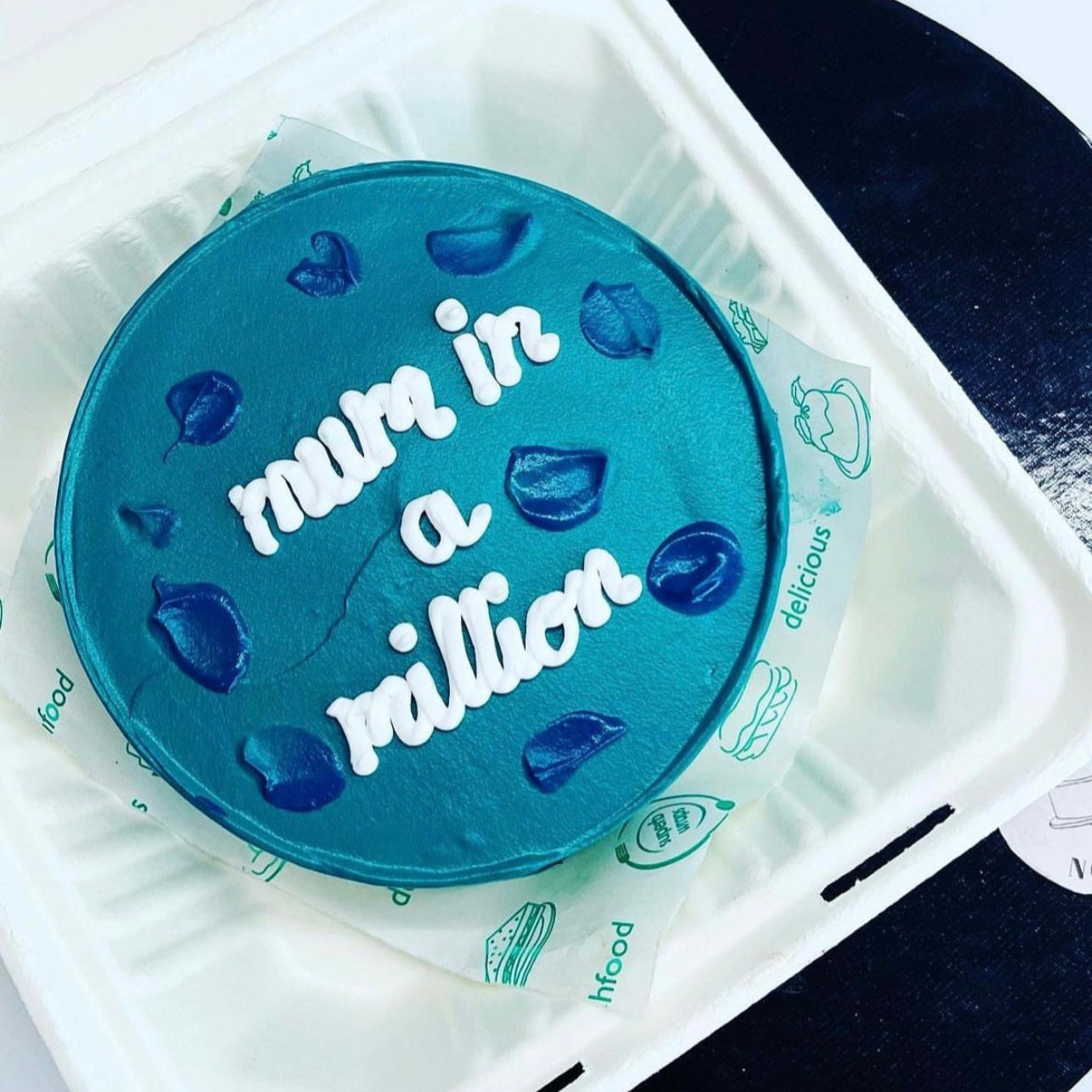A blue cake adorned with the phrase "Mum in a Million" elegantly written on its surface.