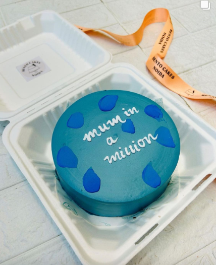 A blue cake adorned with the phrase "Mum in a Million" elegantly written on its surface.