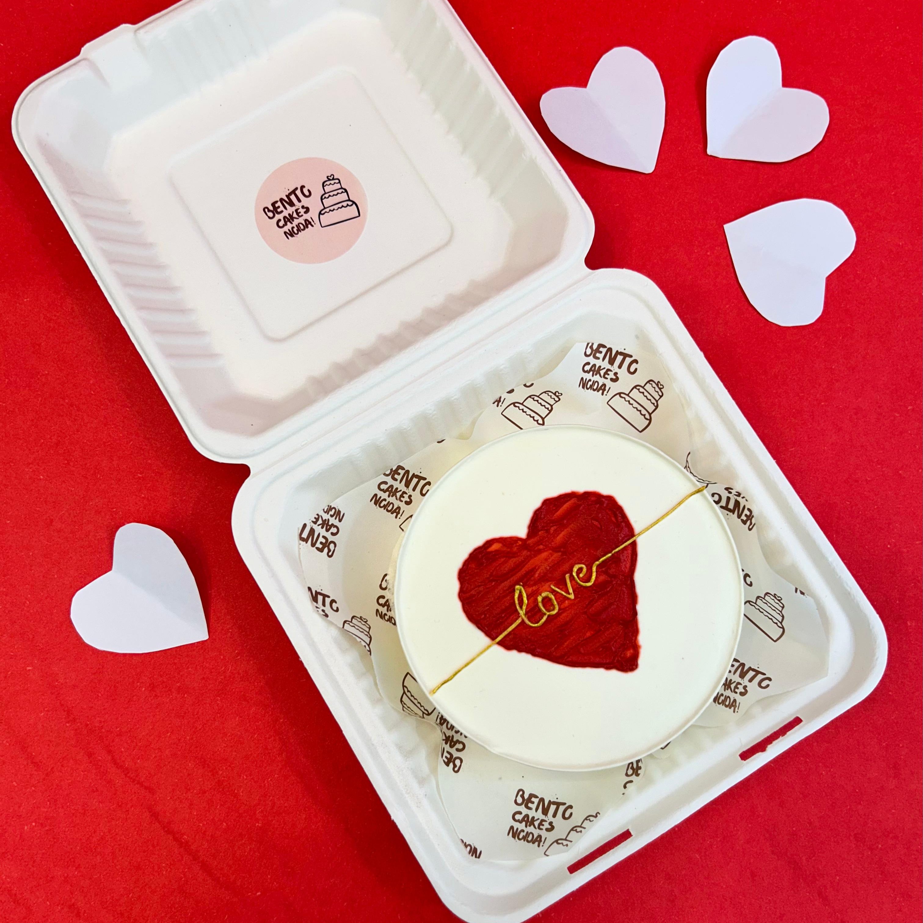 A bento box featuring a red heart design on its surface, symbolizing love and affection.
