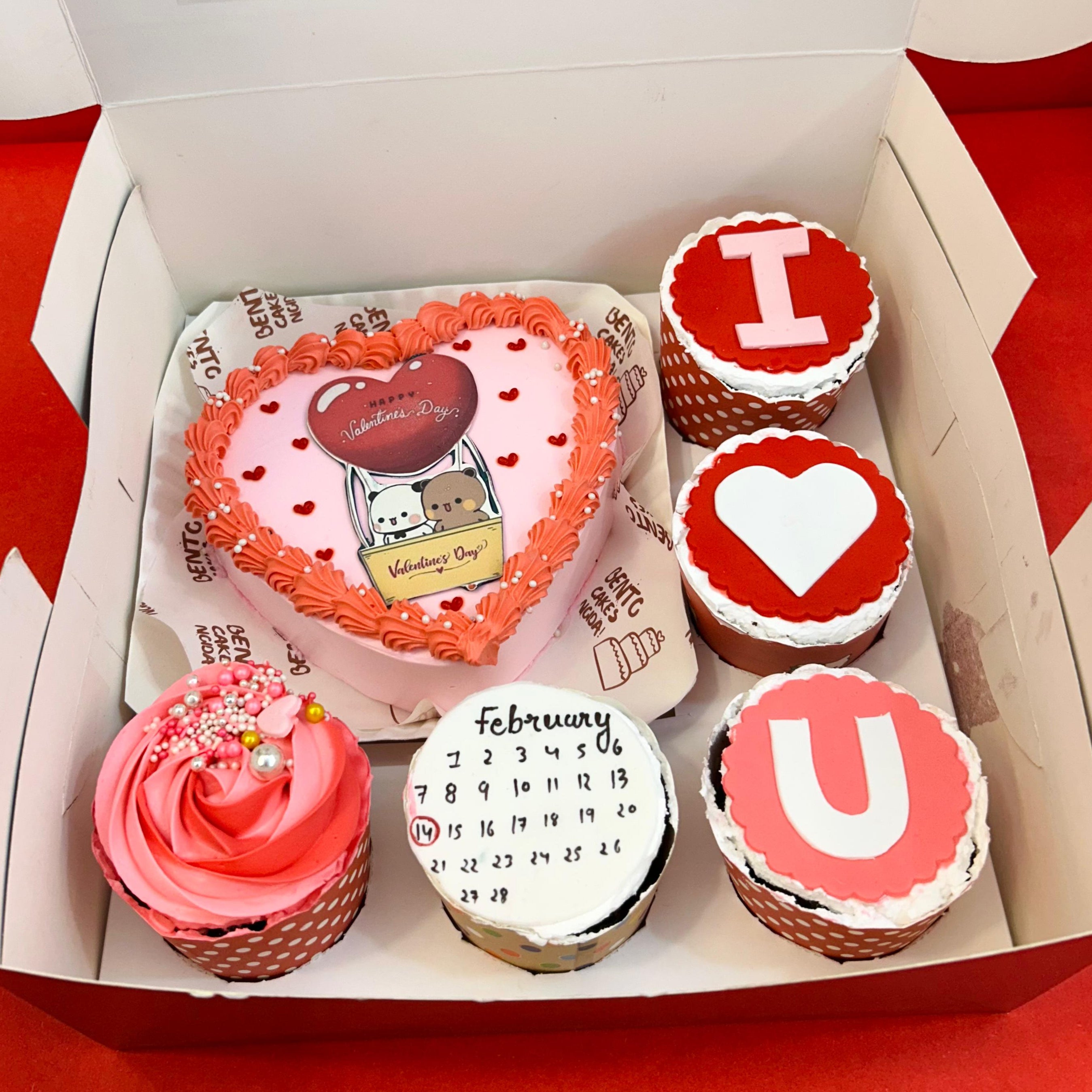 Valentine's Day cupcakes arranged in a box, complemented by a charming bento cake for a festive treat.