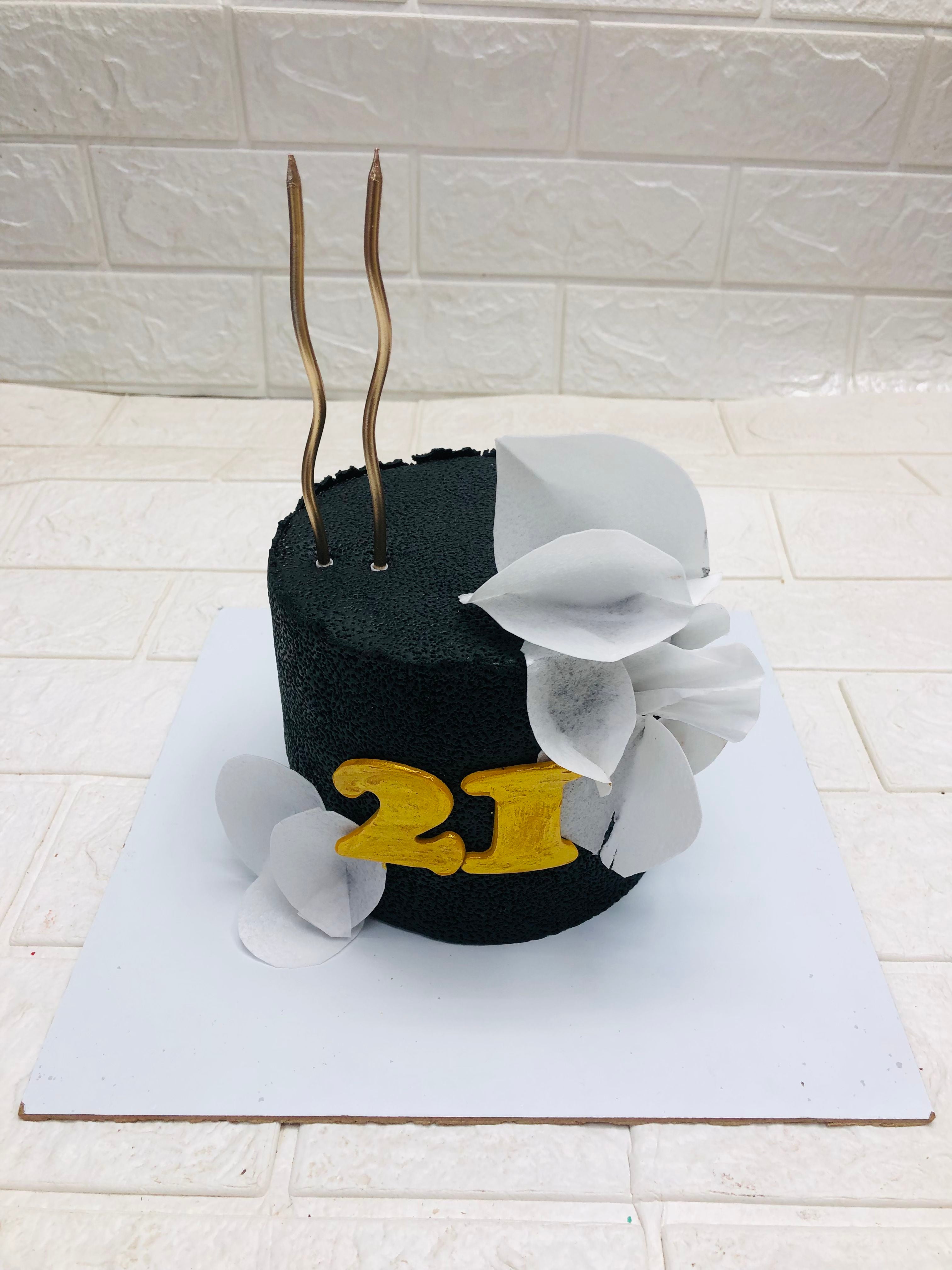 A vibrant black and yellow cake decorated with the number 21, perfect for a birthday celebration.