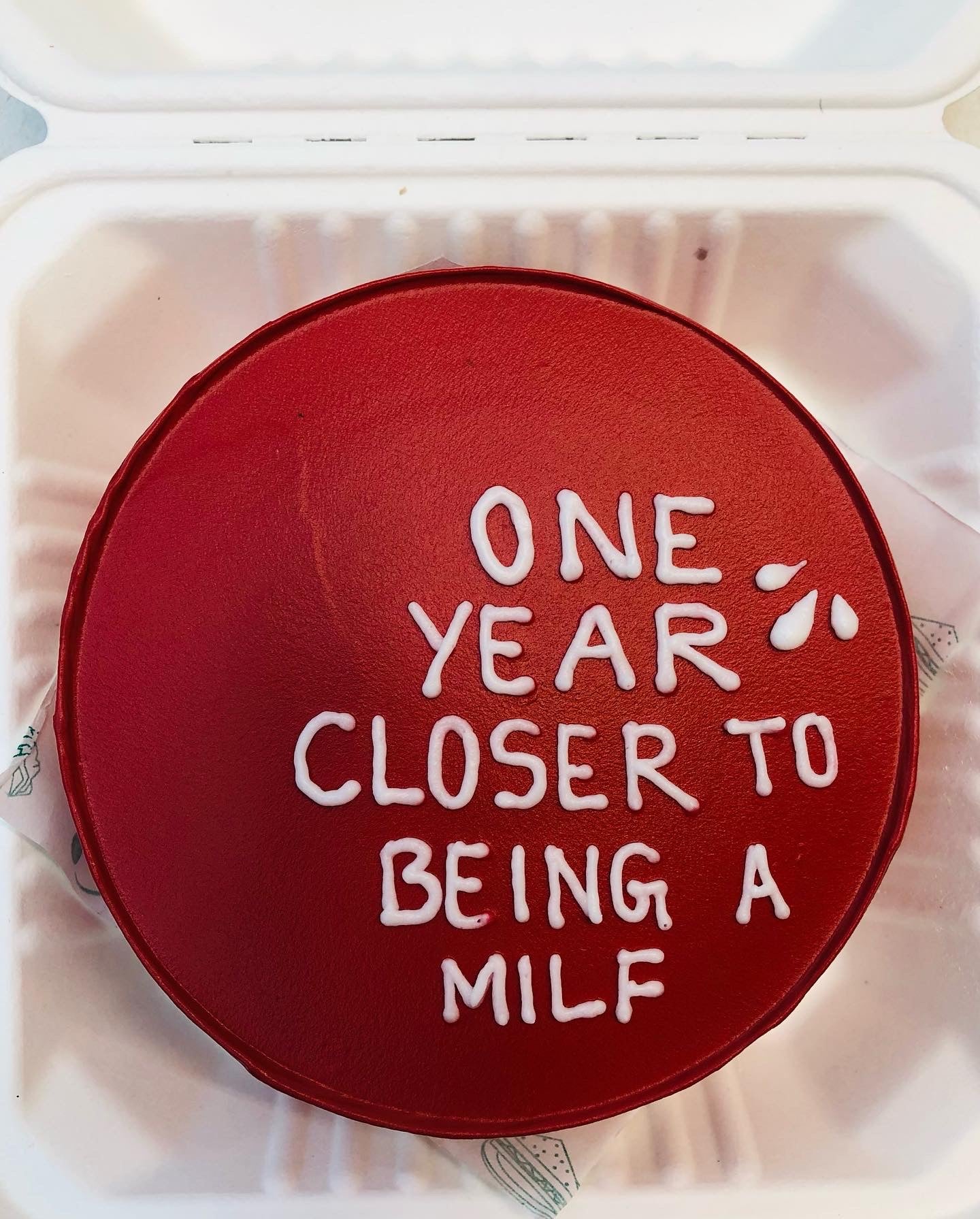 A vibrant red cake featuring elegant writing, perfect for a special occasion or celebration.