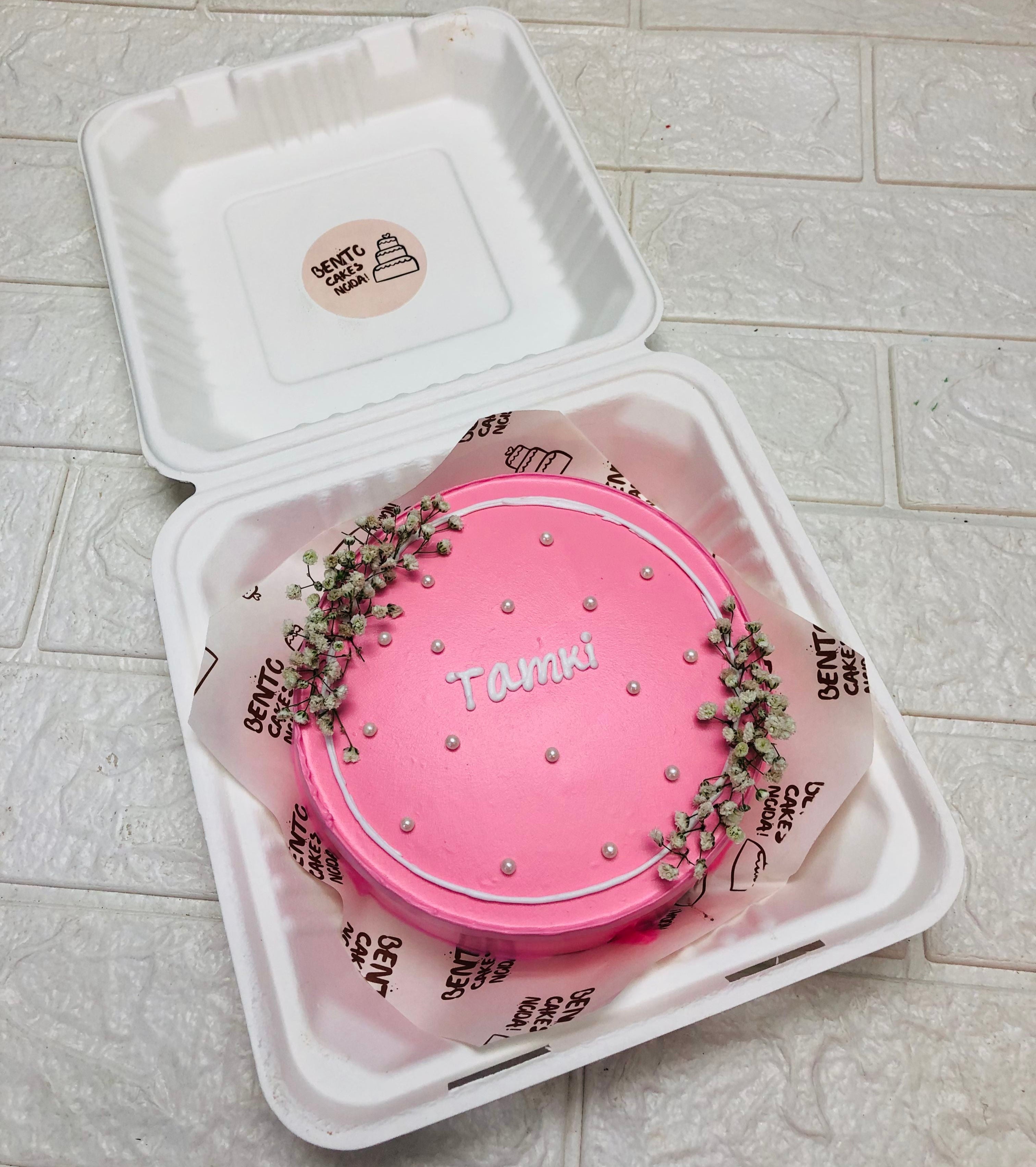 A vintage pink bento cake decorated with vintage white florals.