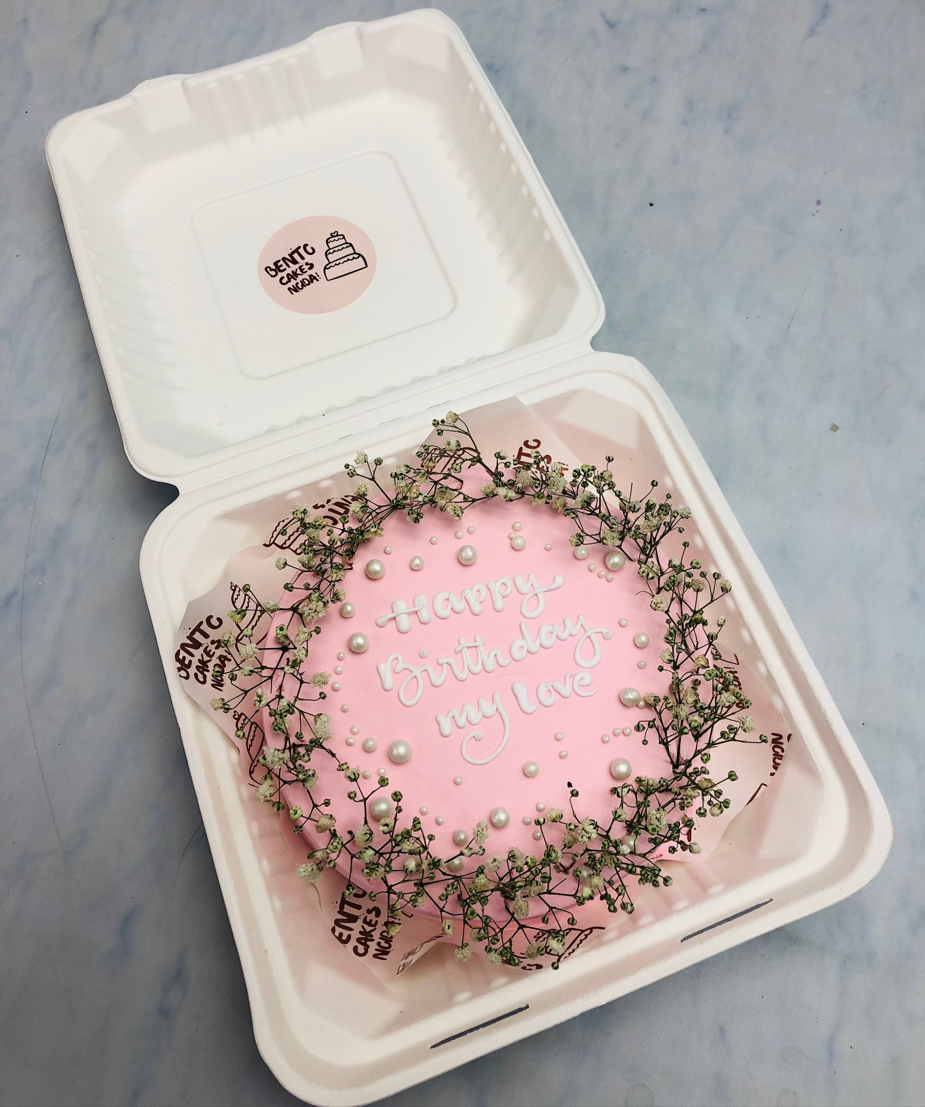 A baby pink bento cake decorated with vintage florals and white sprinkles for birthday.