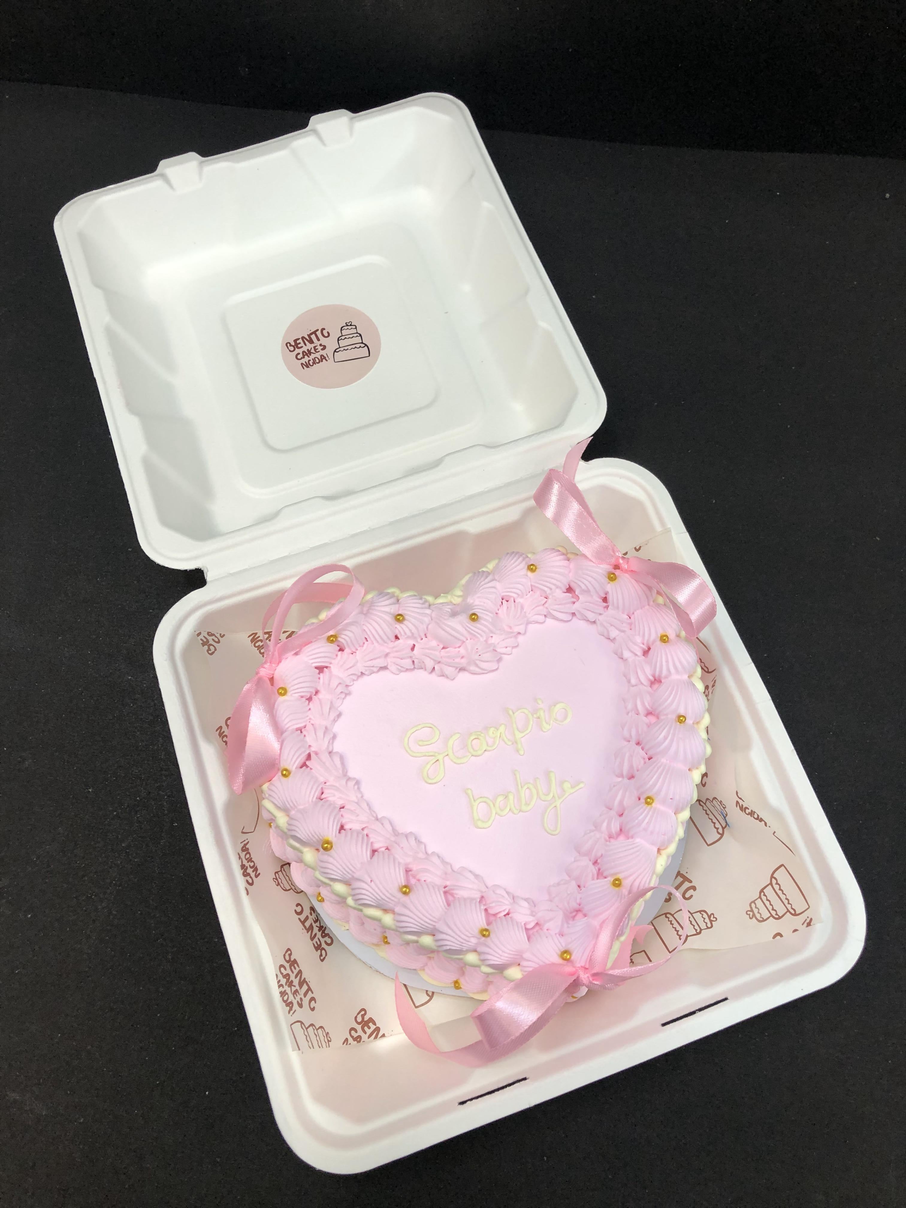A light pink designer heart shape bento cake with pink bows on it.